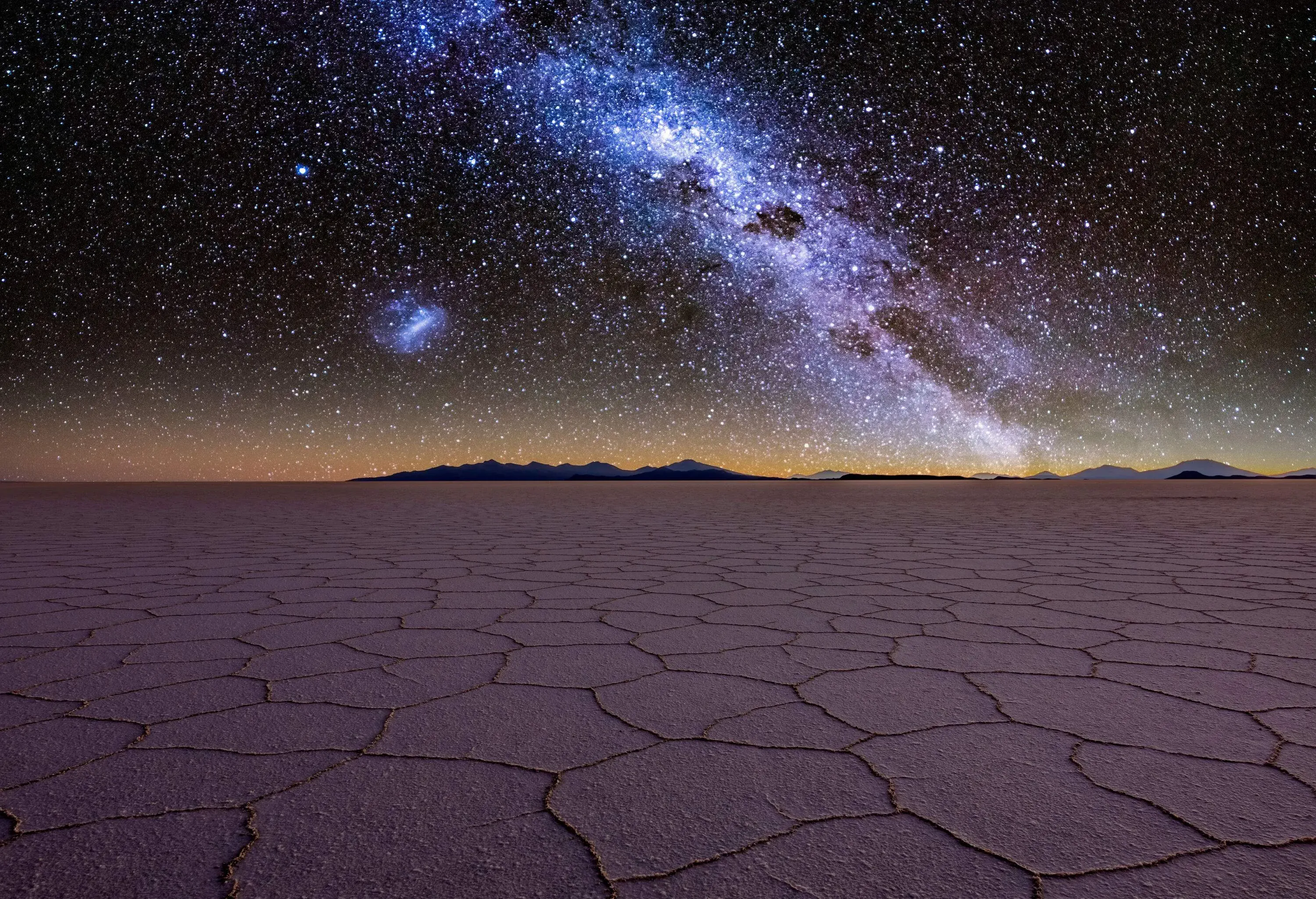A broad salt flat under the Milky Way stretching across the night sky.