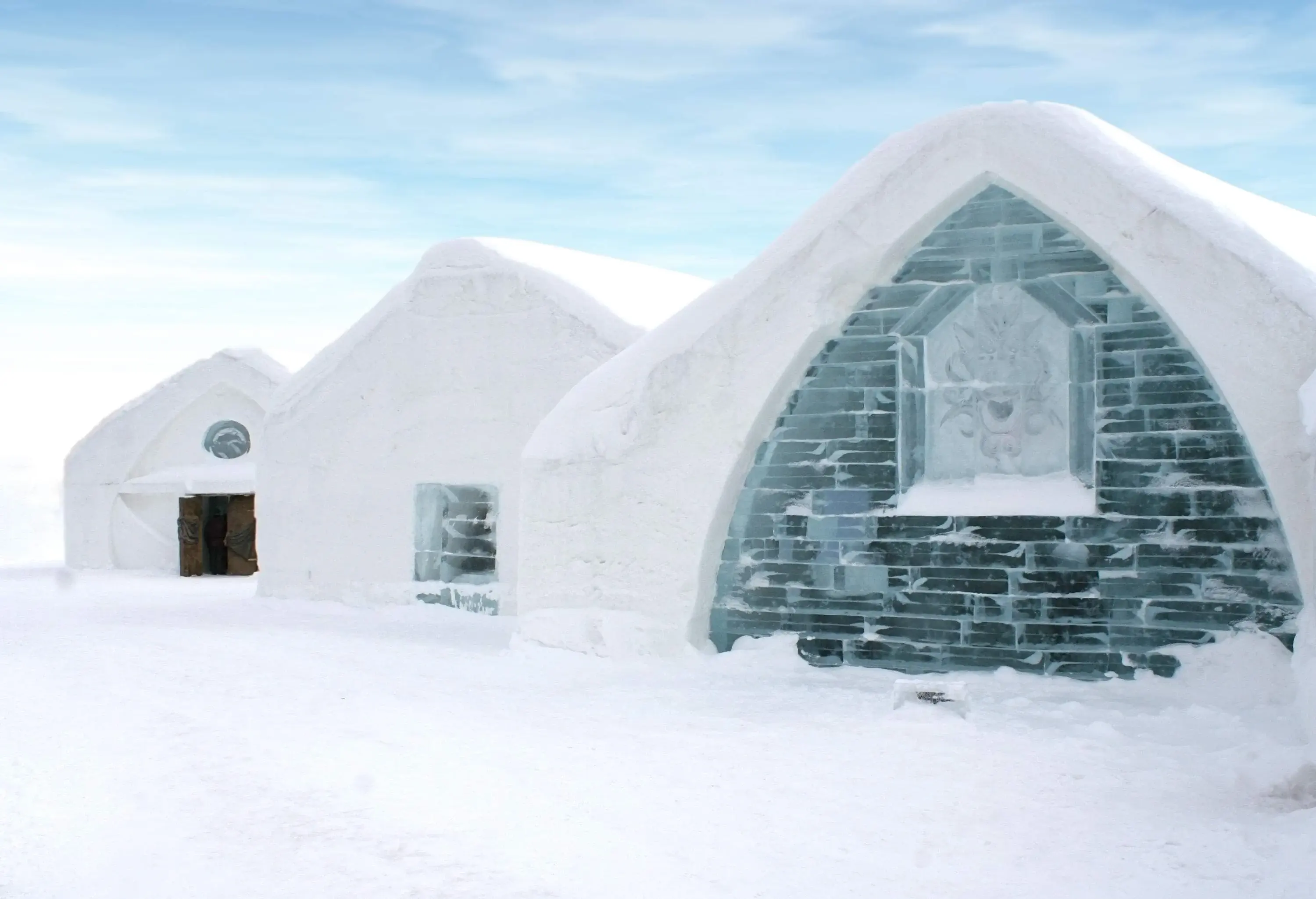 Three sculpted ice cottages on a freezing and pristine white snowfield.