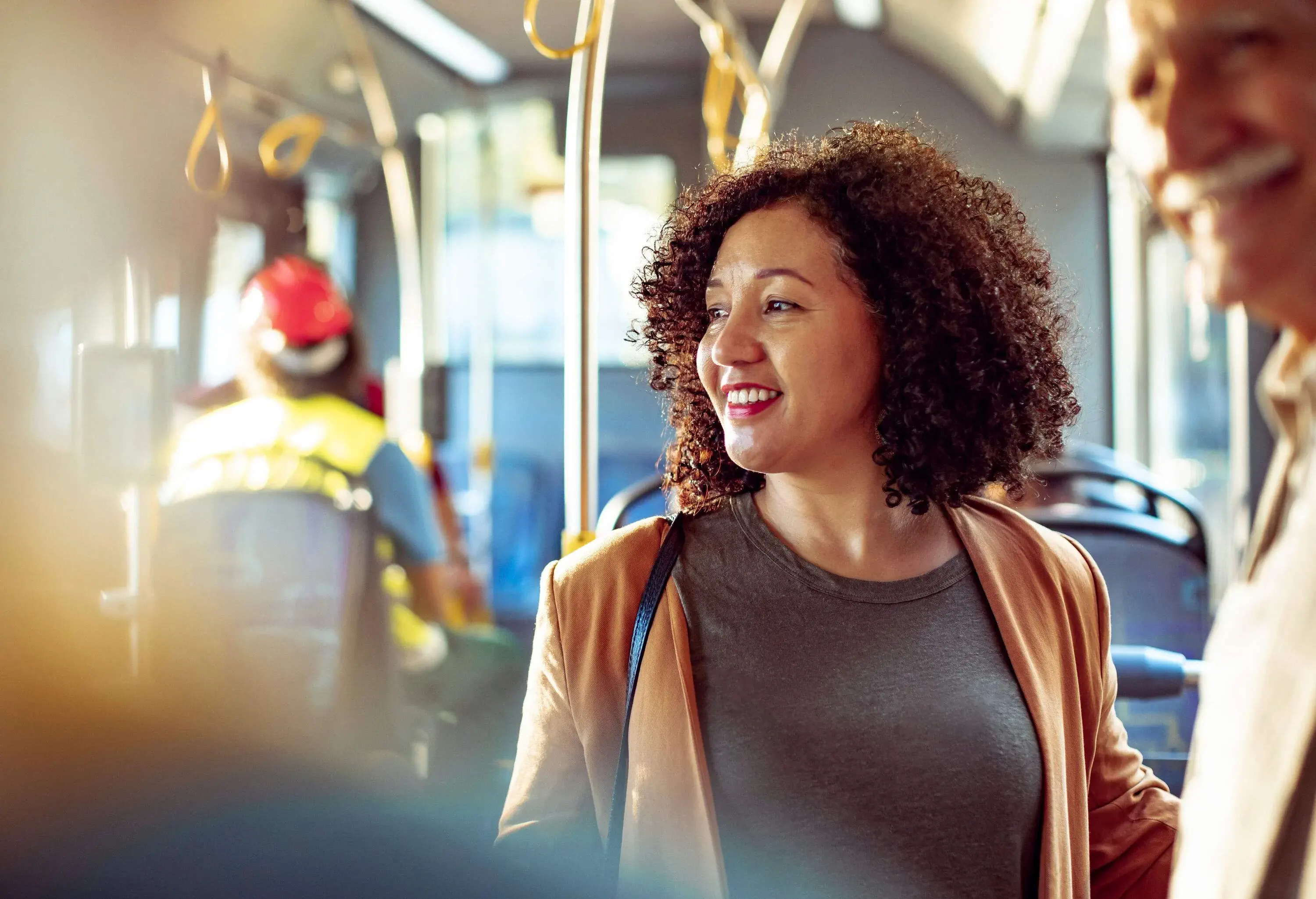 Portrait of a happy woman among other passengers inside a bus.