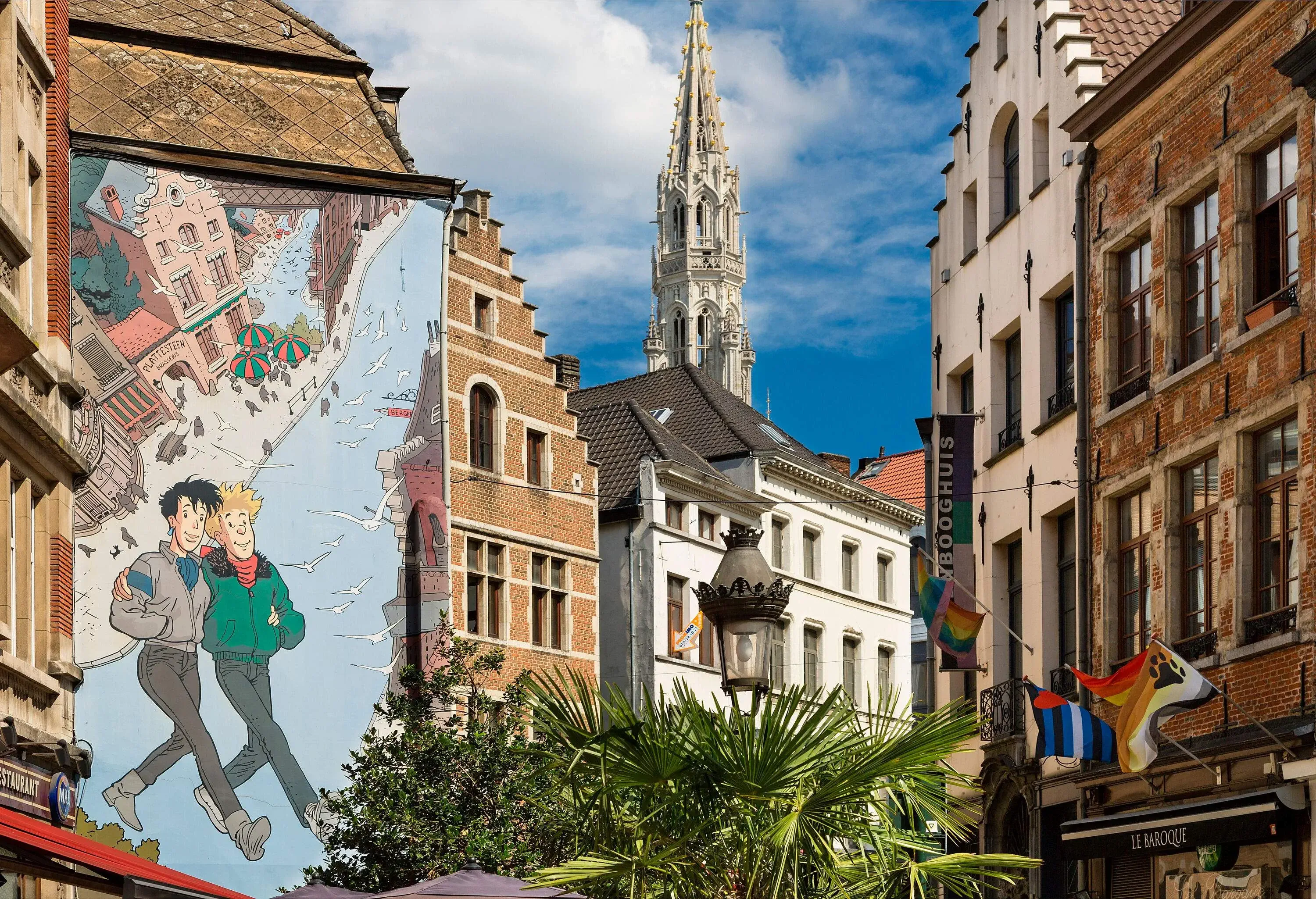 A quirky city centre with a large painting and colourful flags fluttering from buildings.