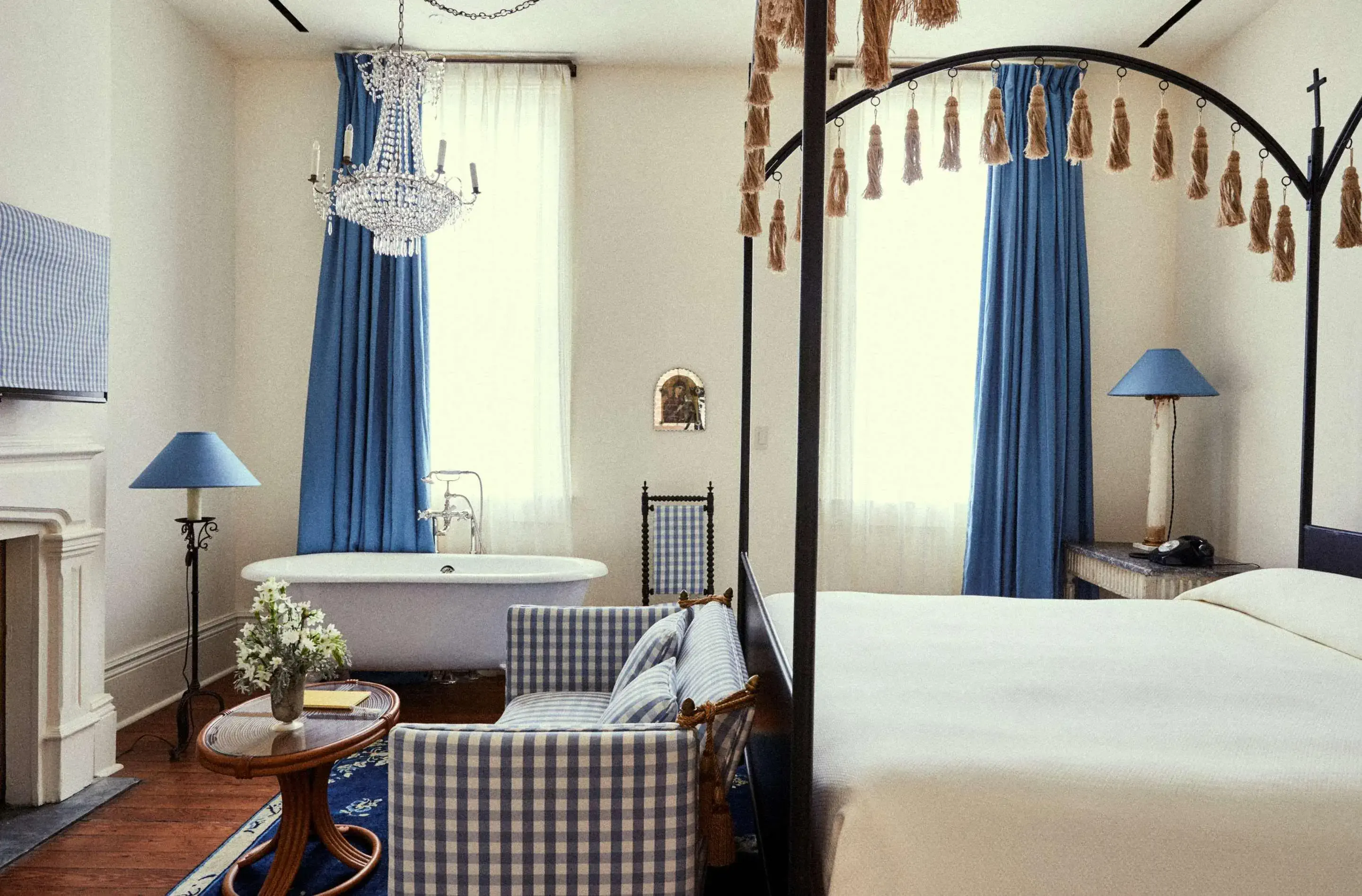 Interior view of a classically decorated hotel room with white and blue colour scheme, four poster bed and foot claw bathtub in the room