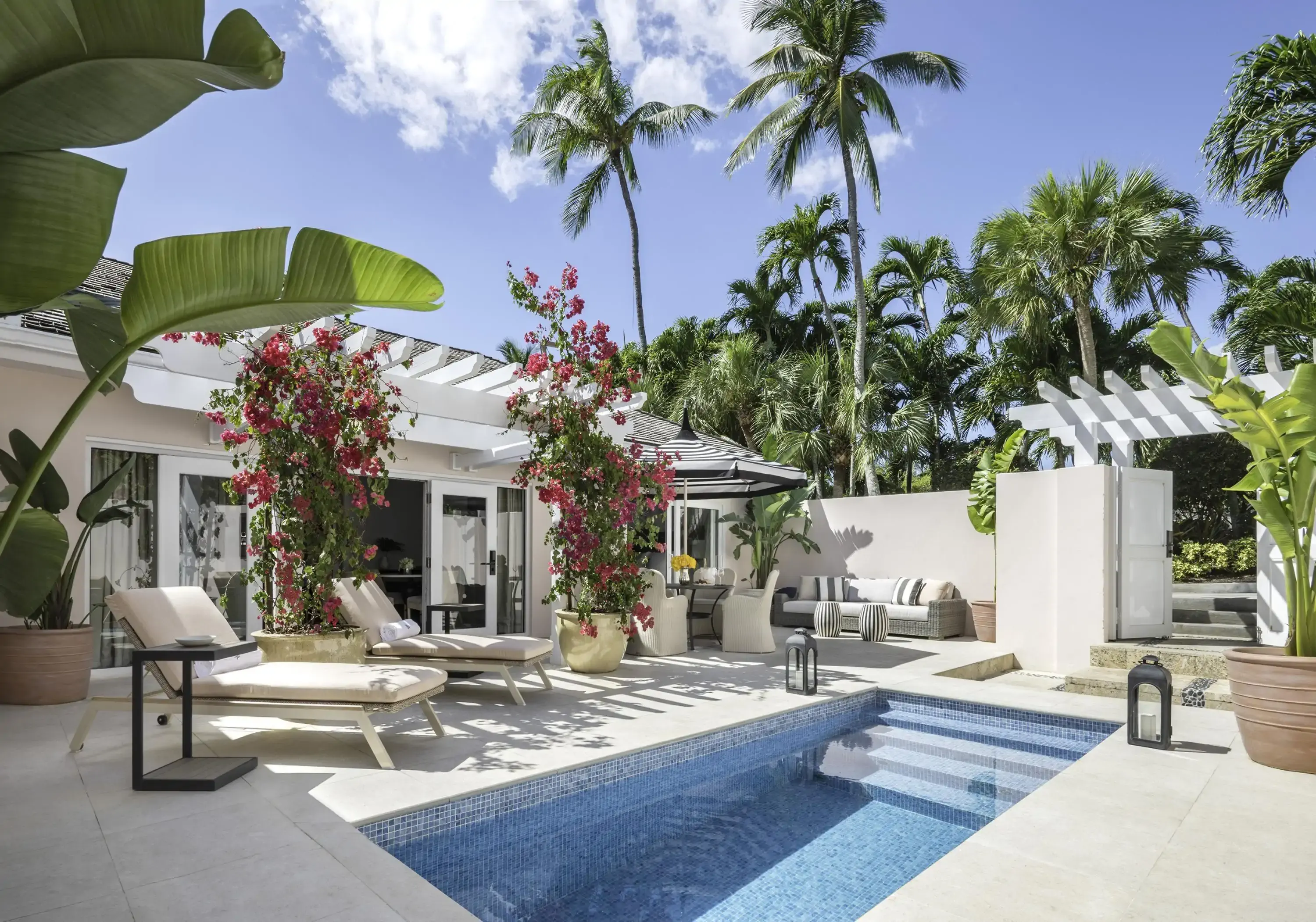 Private patio with pool and tropical garden foliage on a sunny day