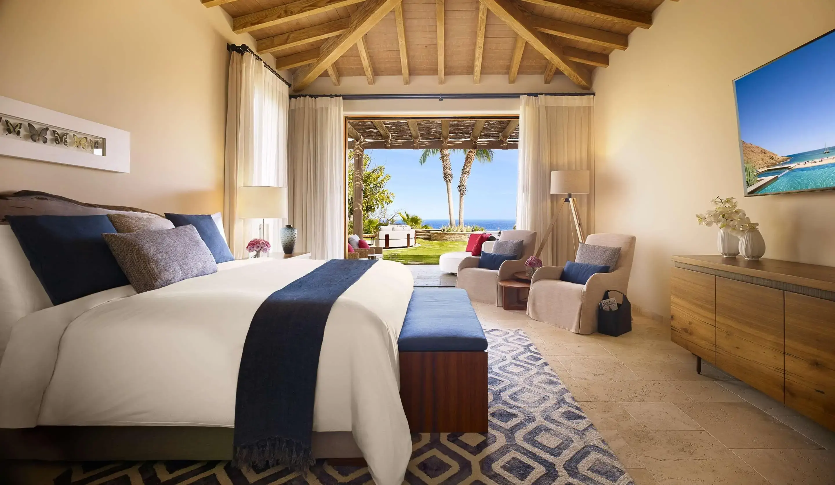 Interior of modern tropical hotel room with white and blue colour scheme with view onto the terrace and garden with seaview