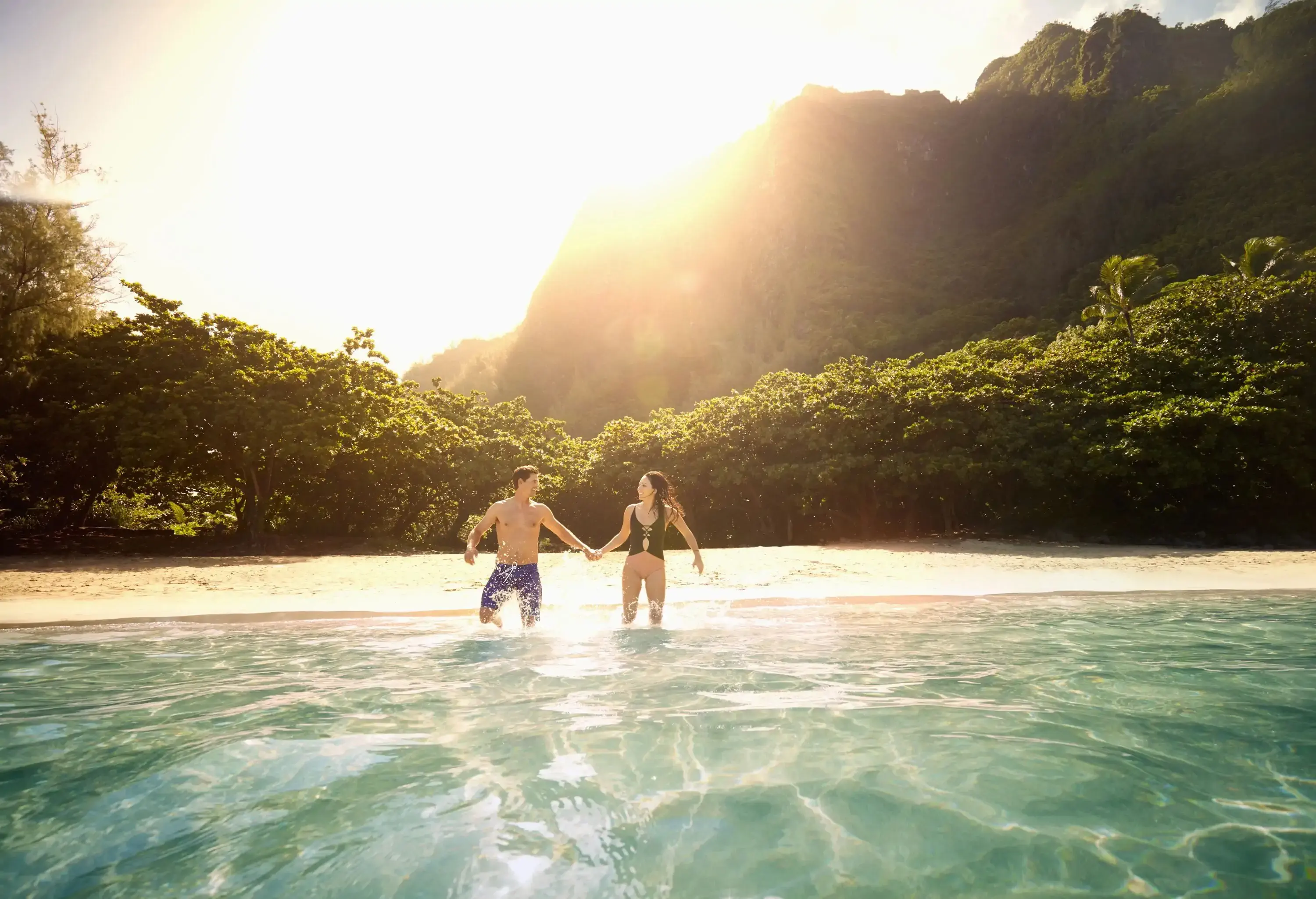 View from the water of couple running into the sea on a tropical beach