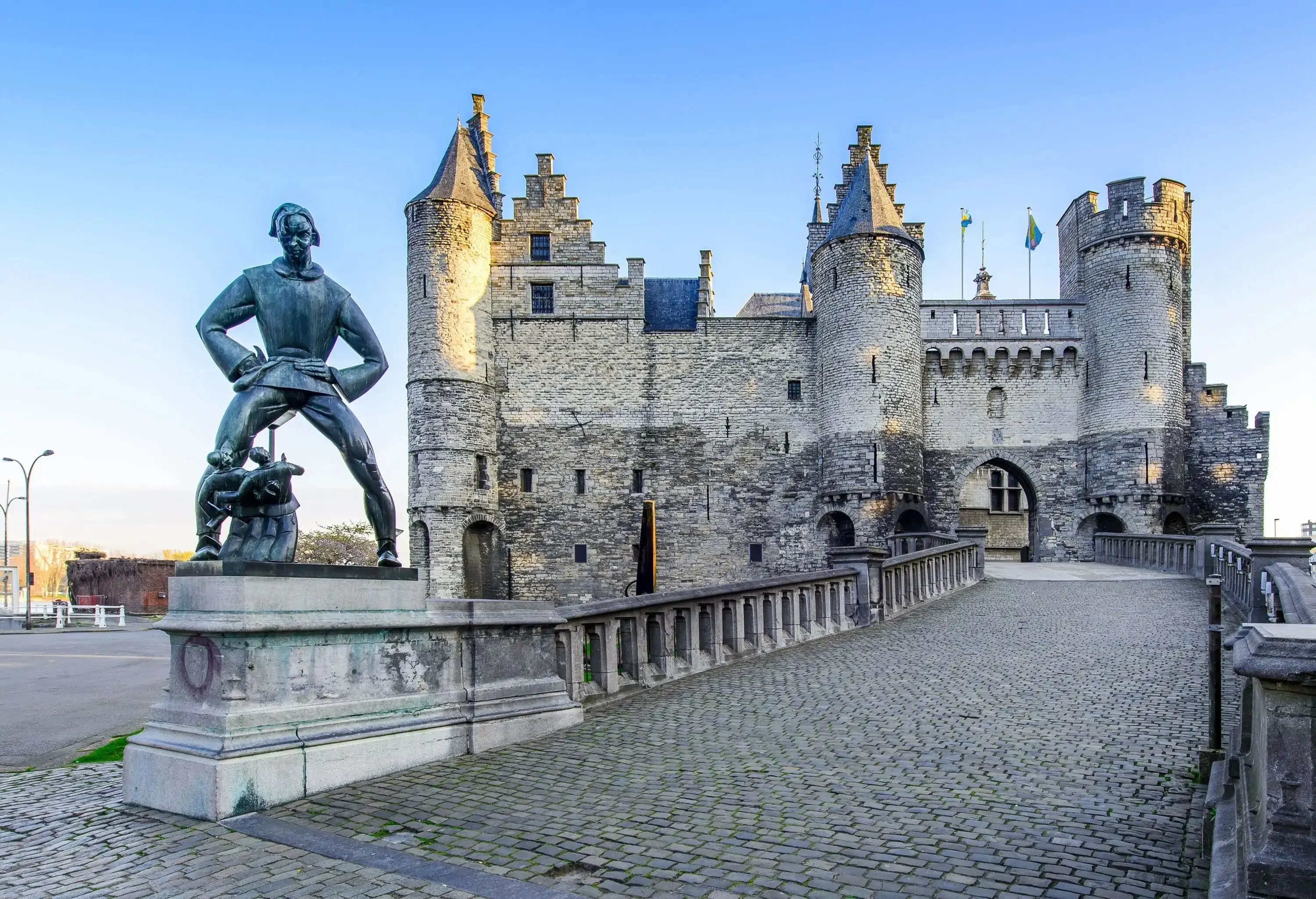 Imposing medieval castle with a statue in the foreground on a sunny day