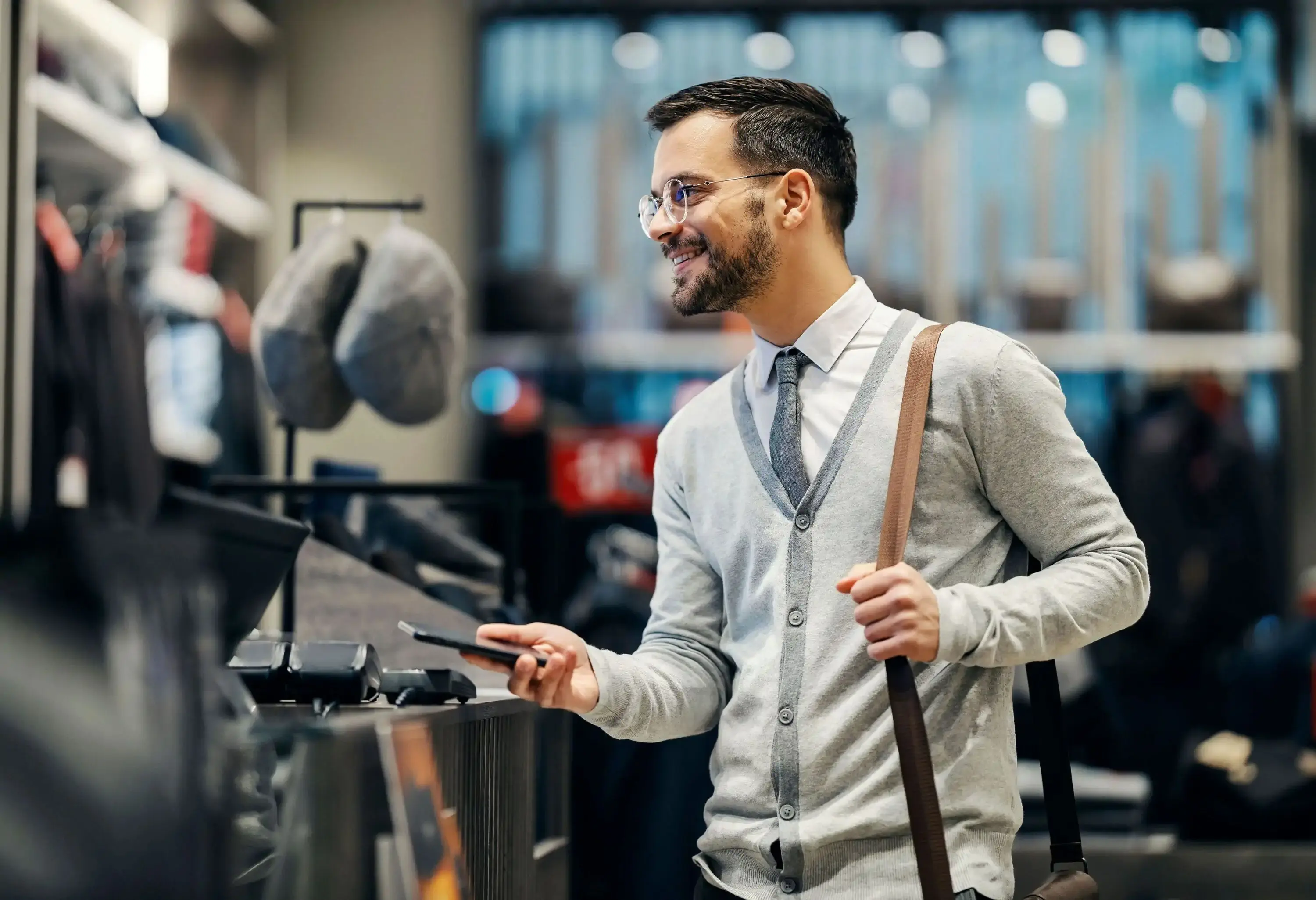 A smiling man is using smart phone for shopping in a boutique.