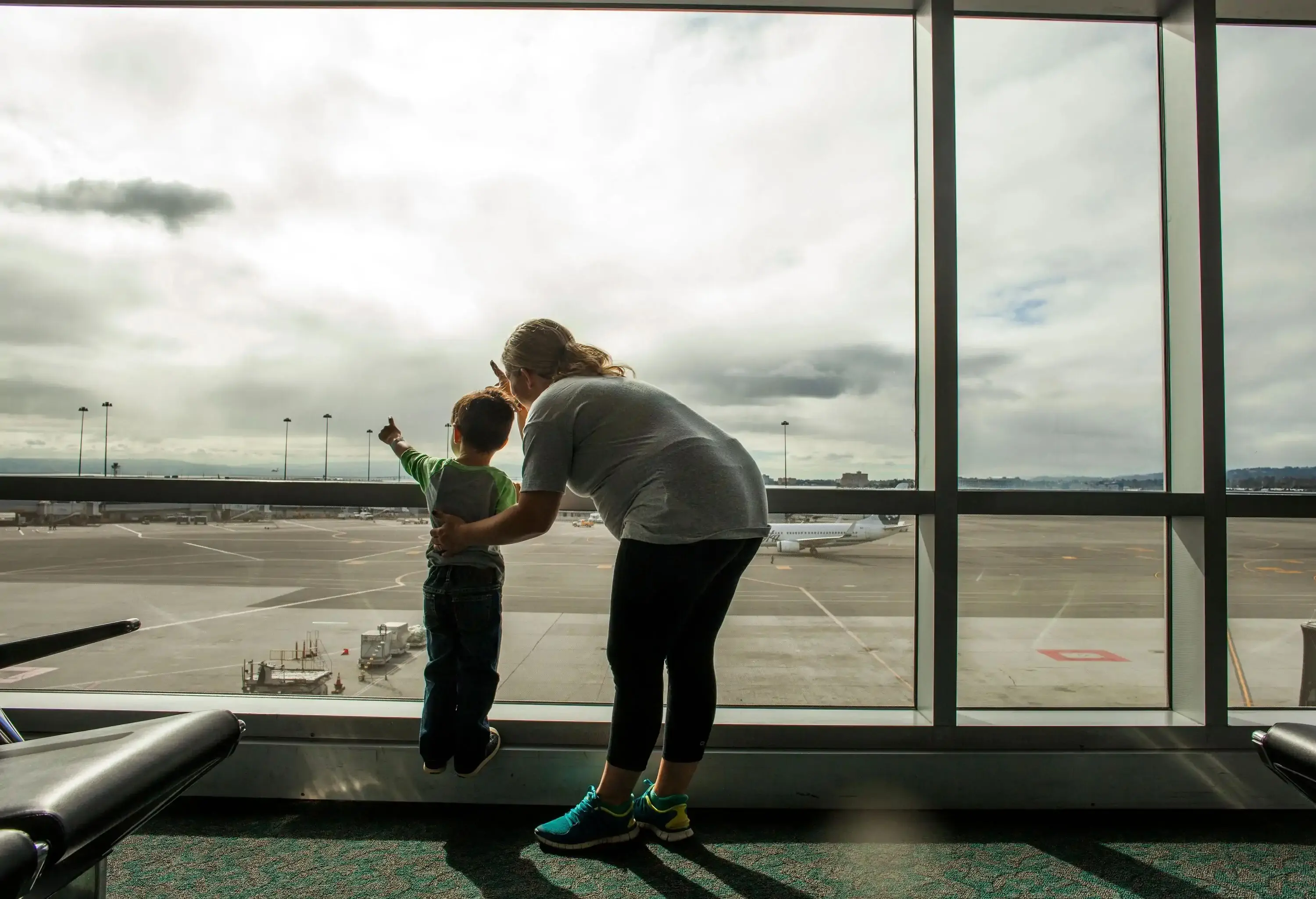 Mother and young child looking out airport window