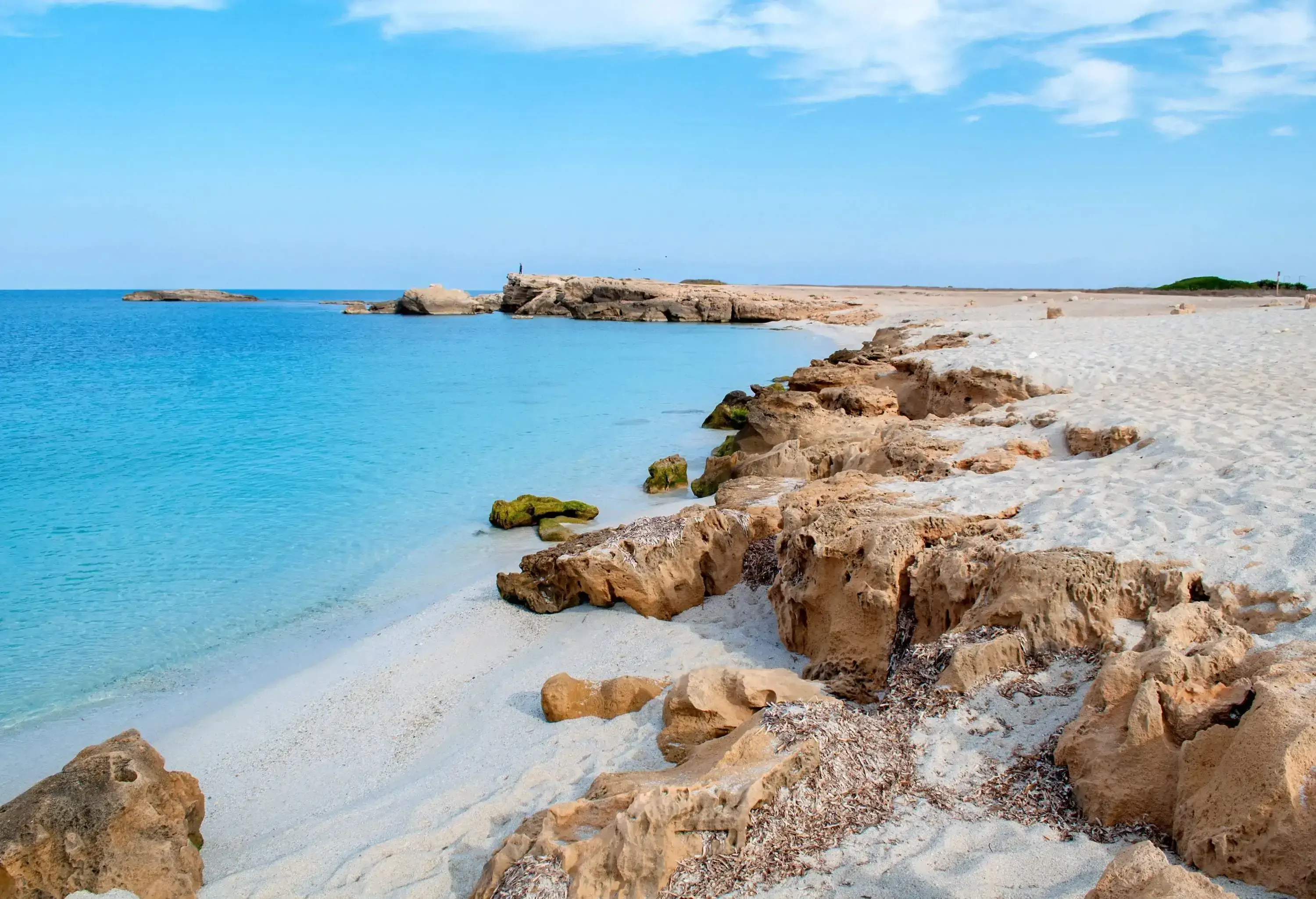 A rocky white fine sand beach with crystalline turquoise calm water.