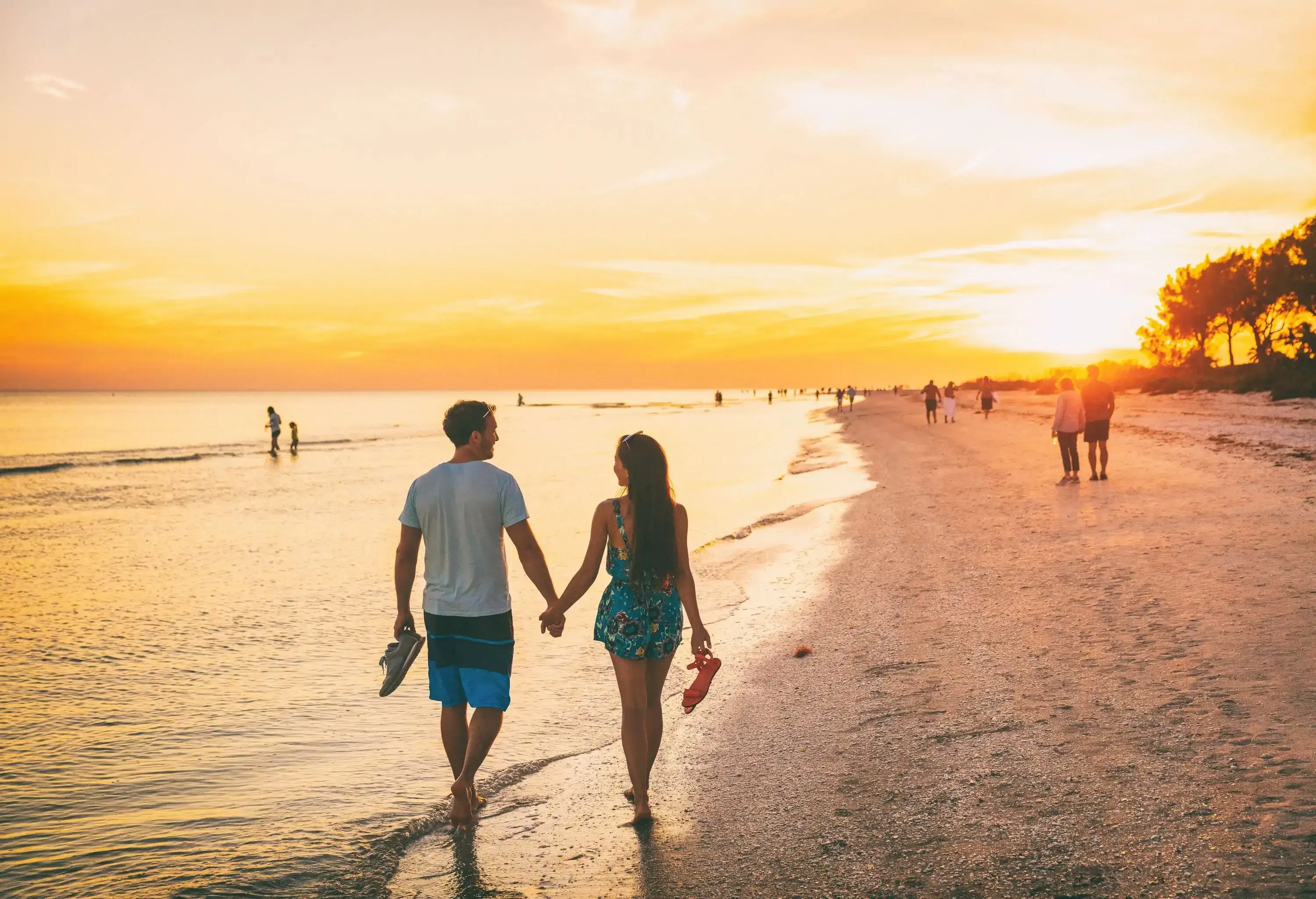 A couple going on a sunset stroll by the beach barefooted.