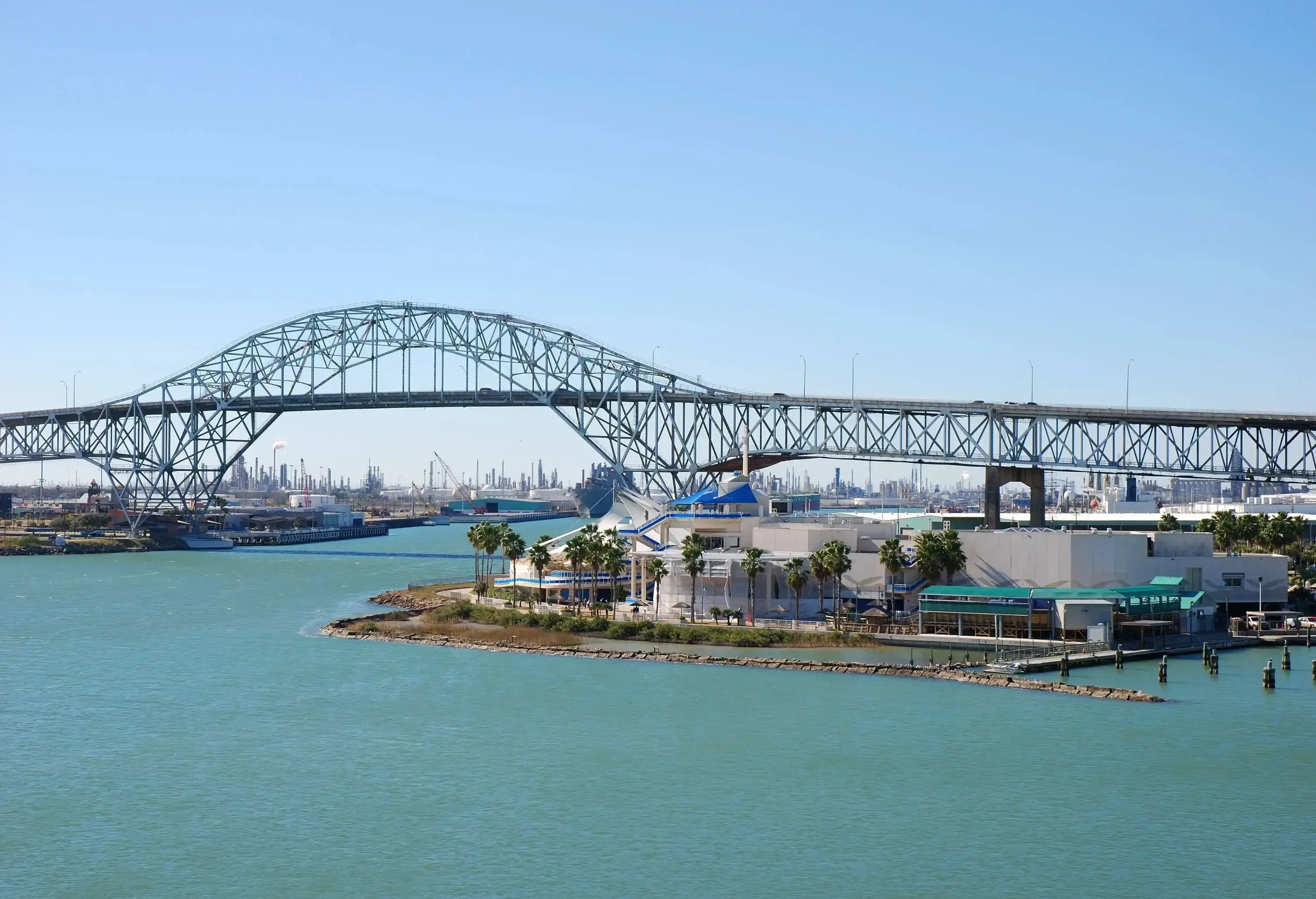A waterfront building offers views of a through arch bridge across a harbour.