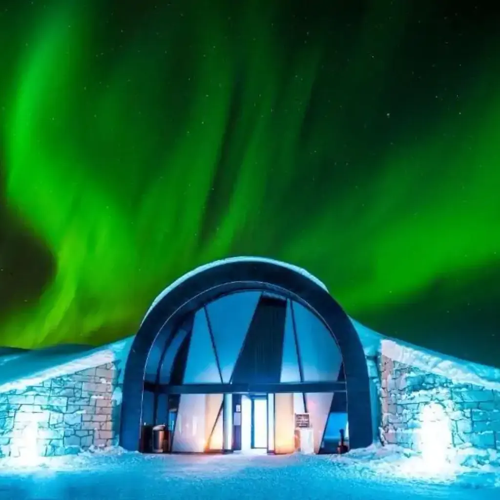A hotel entrance covered in snow with aurora borealis on the night sky