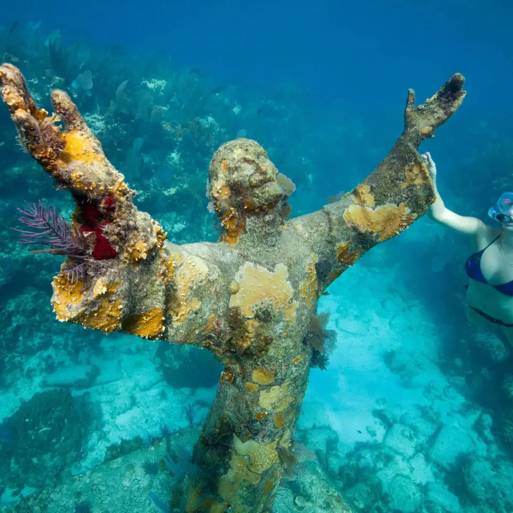 A young woman swimming around the submerged Christ of the Abyss statue.