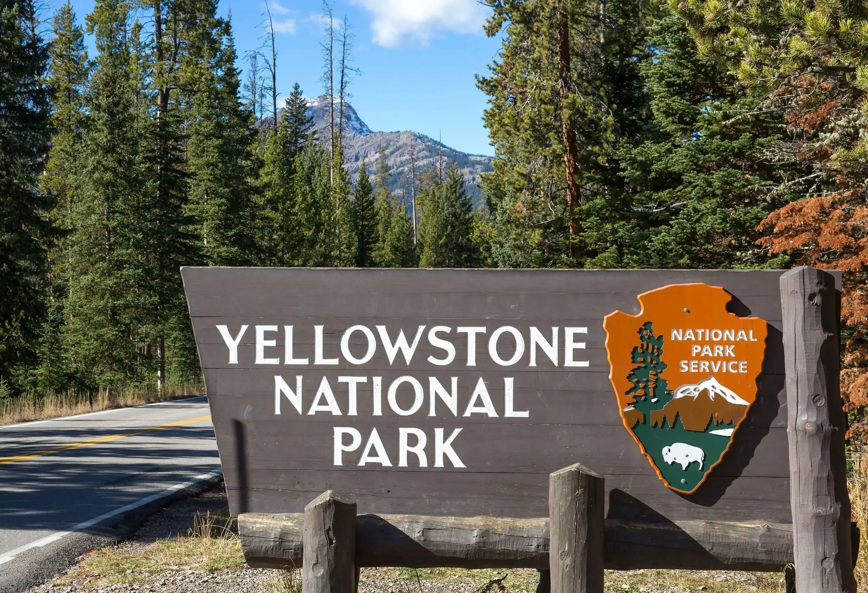 The Yellowstone National Park's sign, painted grey and set on the side of the road.