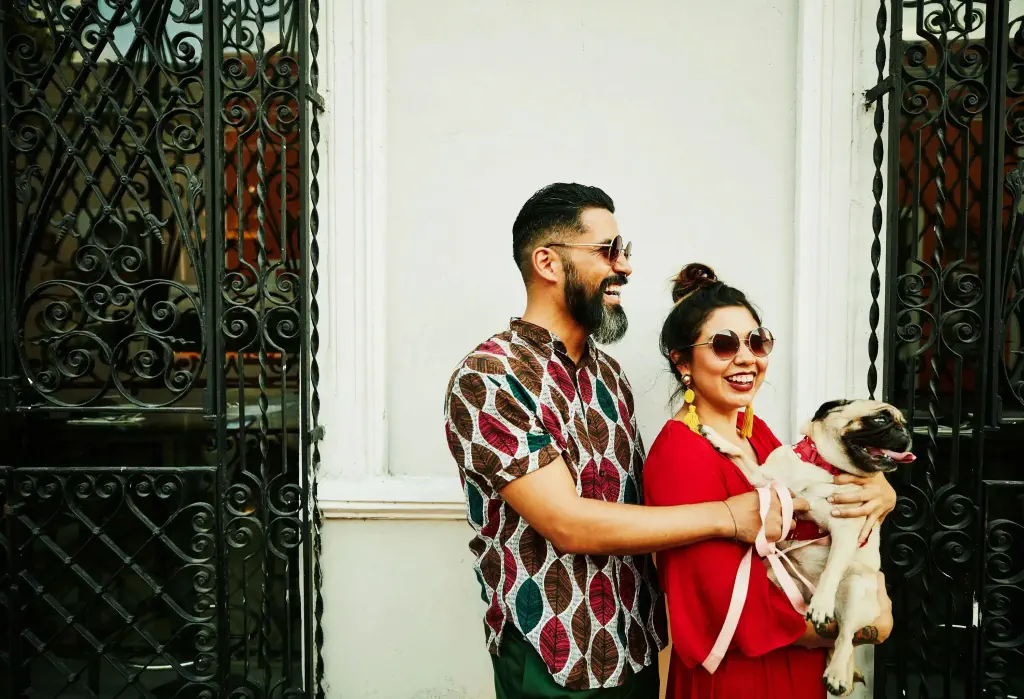A smiling happy couple with the female holding her dog.