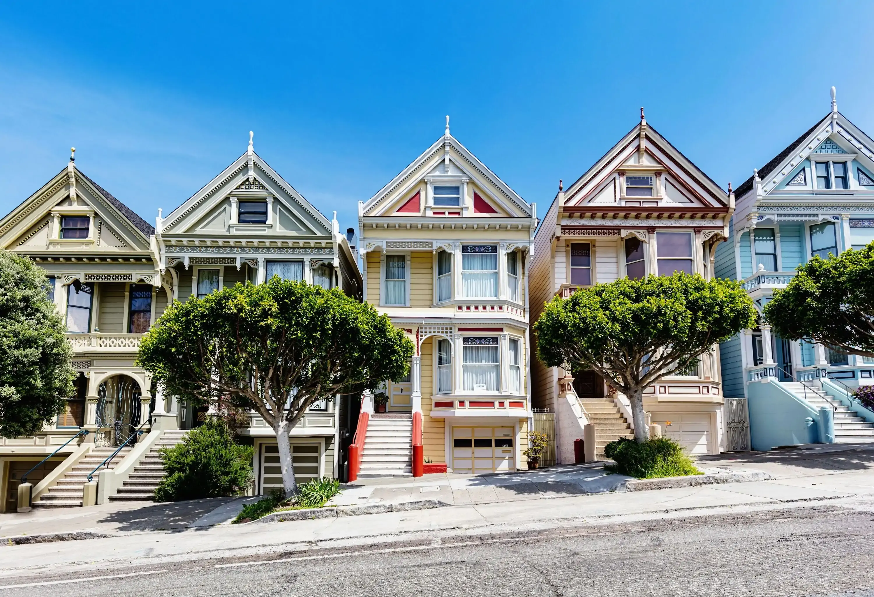A row of colourful Victorian-style houses along a sloping street.