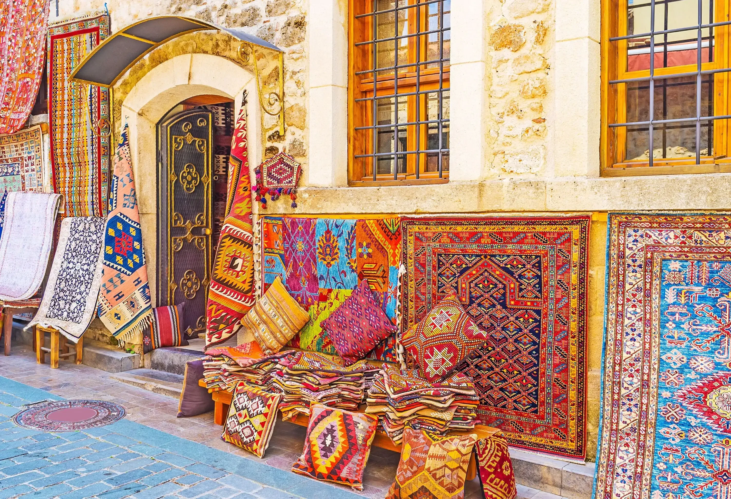 A beautiful assortment of colourful carpets on display on the side of a street.