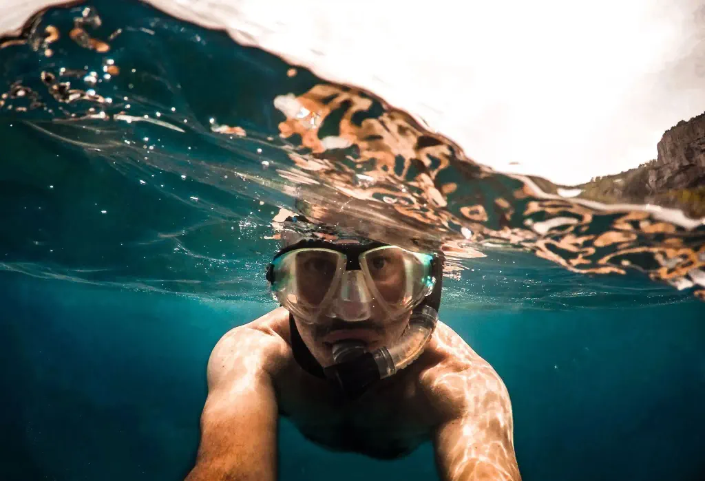 Portrait of a man wearing a scuba diving mask while submerged underwater.
