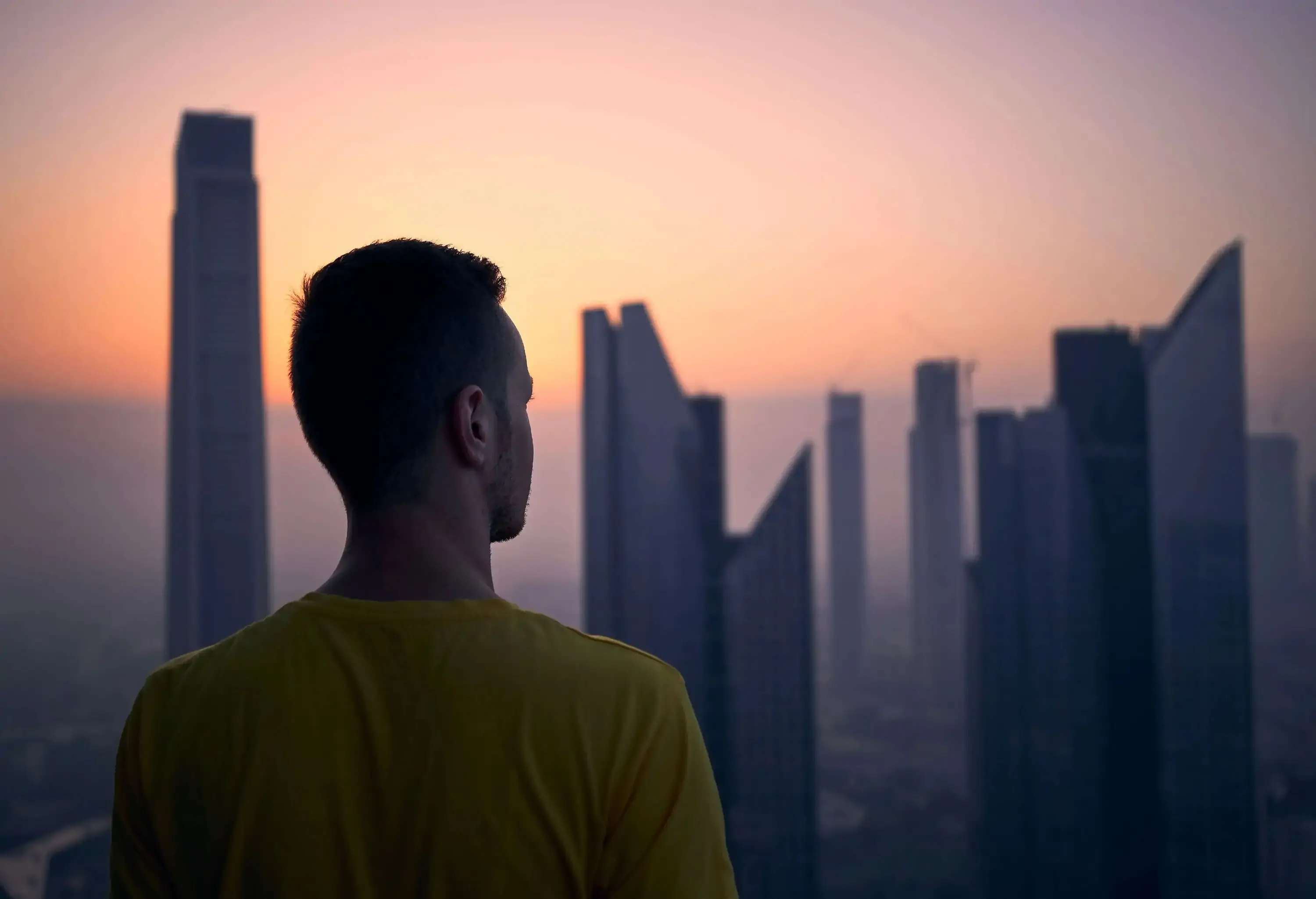 A person in a bokeh backdrop of modern skyscrapers against the calming sunrise sky.