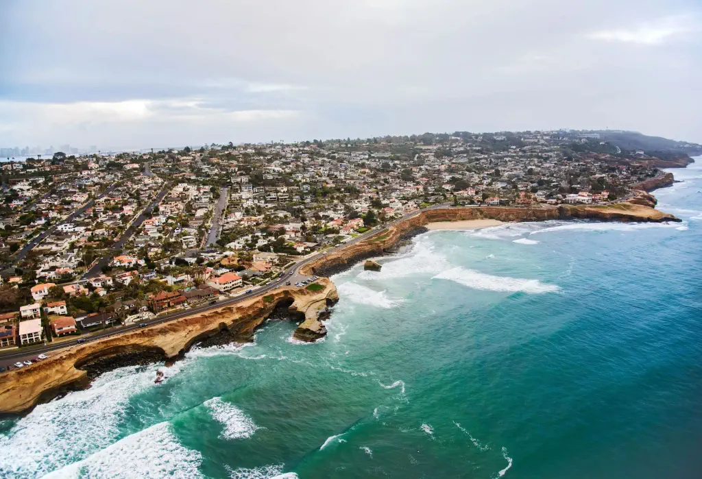 A large city atop a seaside cliff with faces carved by the waves.