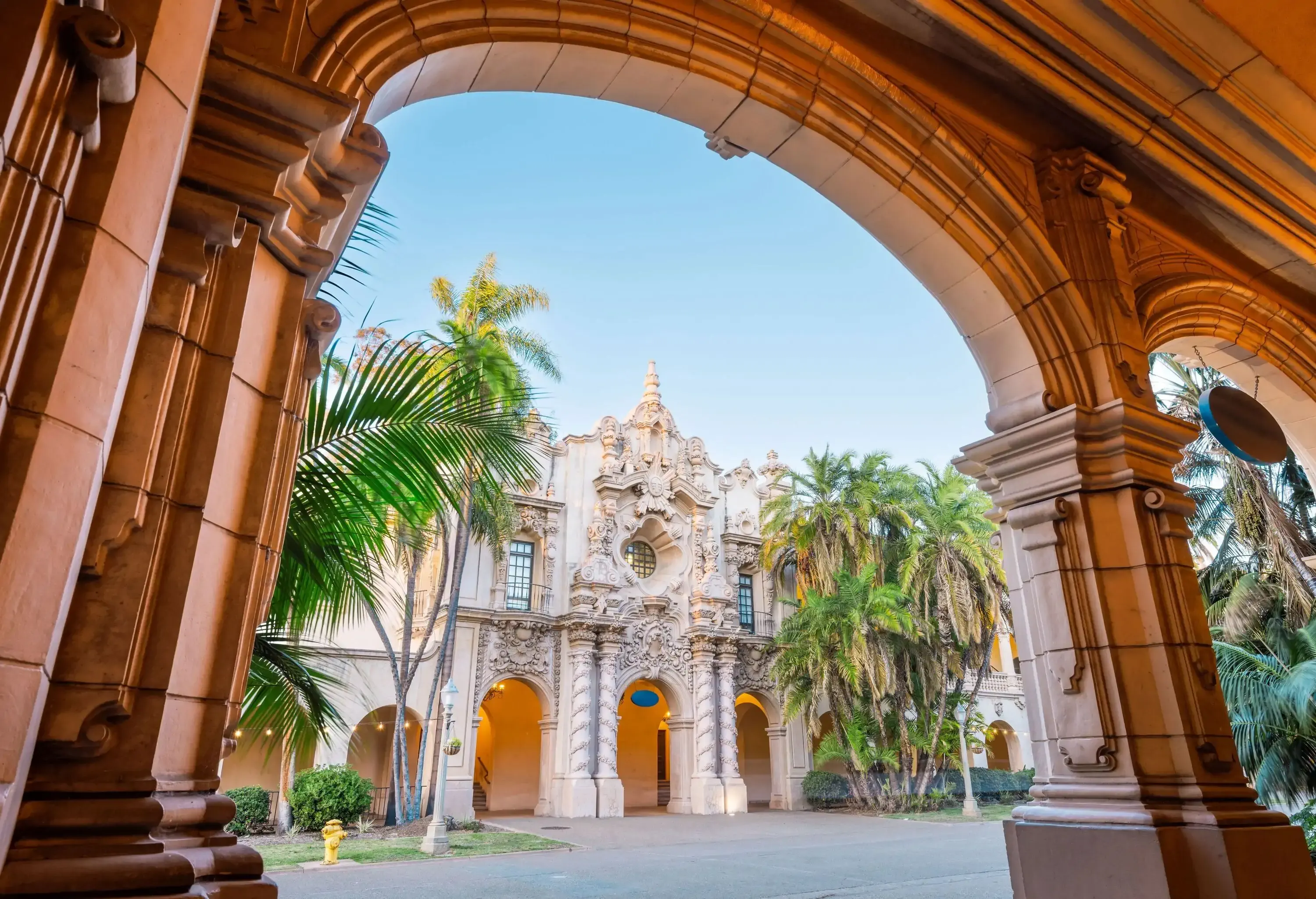A grand, ornate building with intricate carvings and arches, viewed through a stone archway lined with columns.