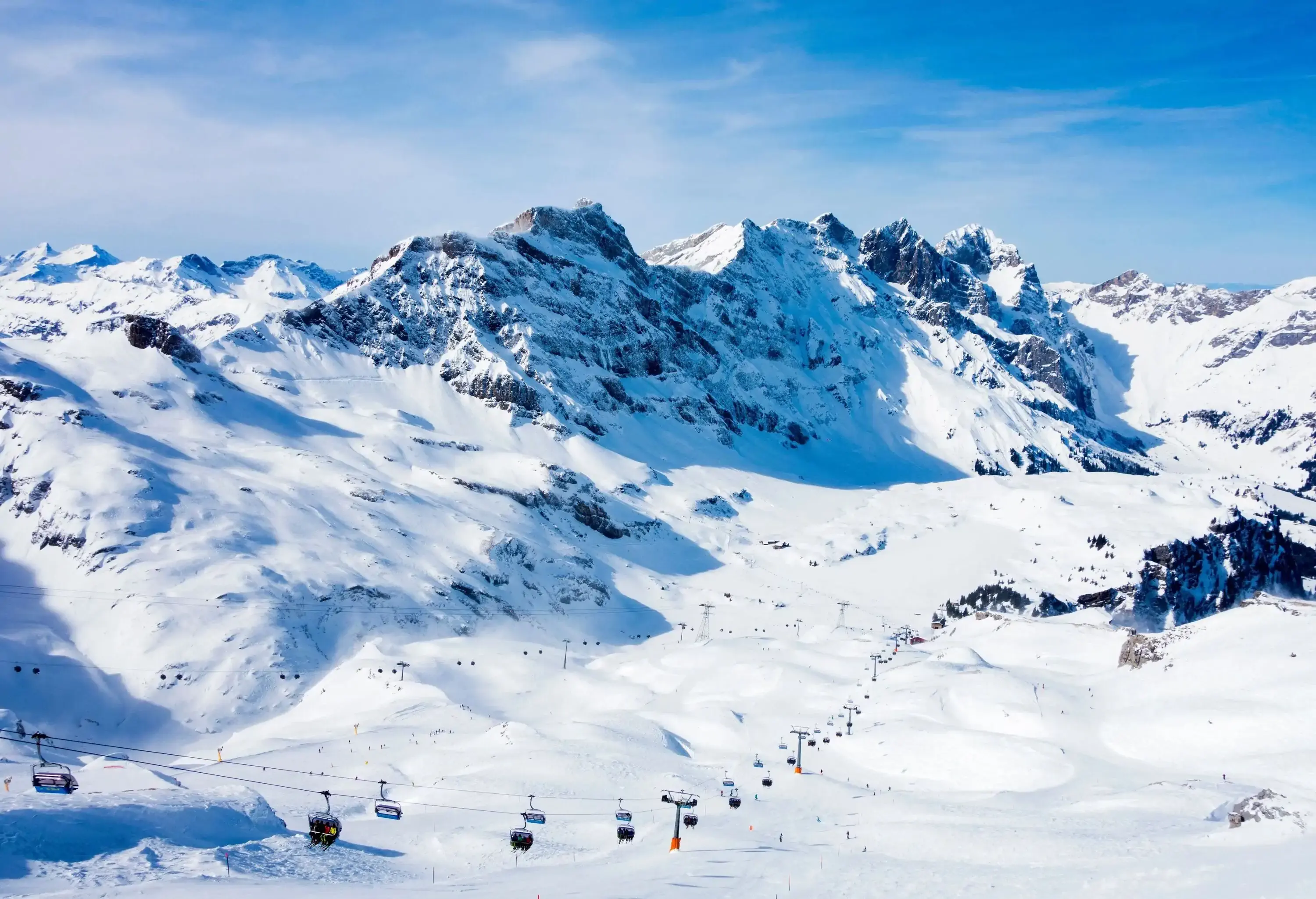 Ski lifts travelling across a snowy mountain landscape.