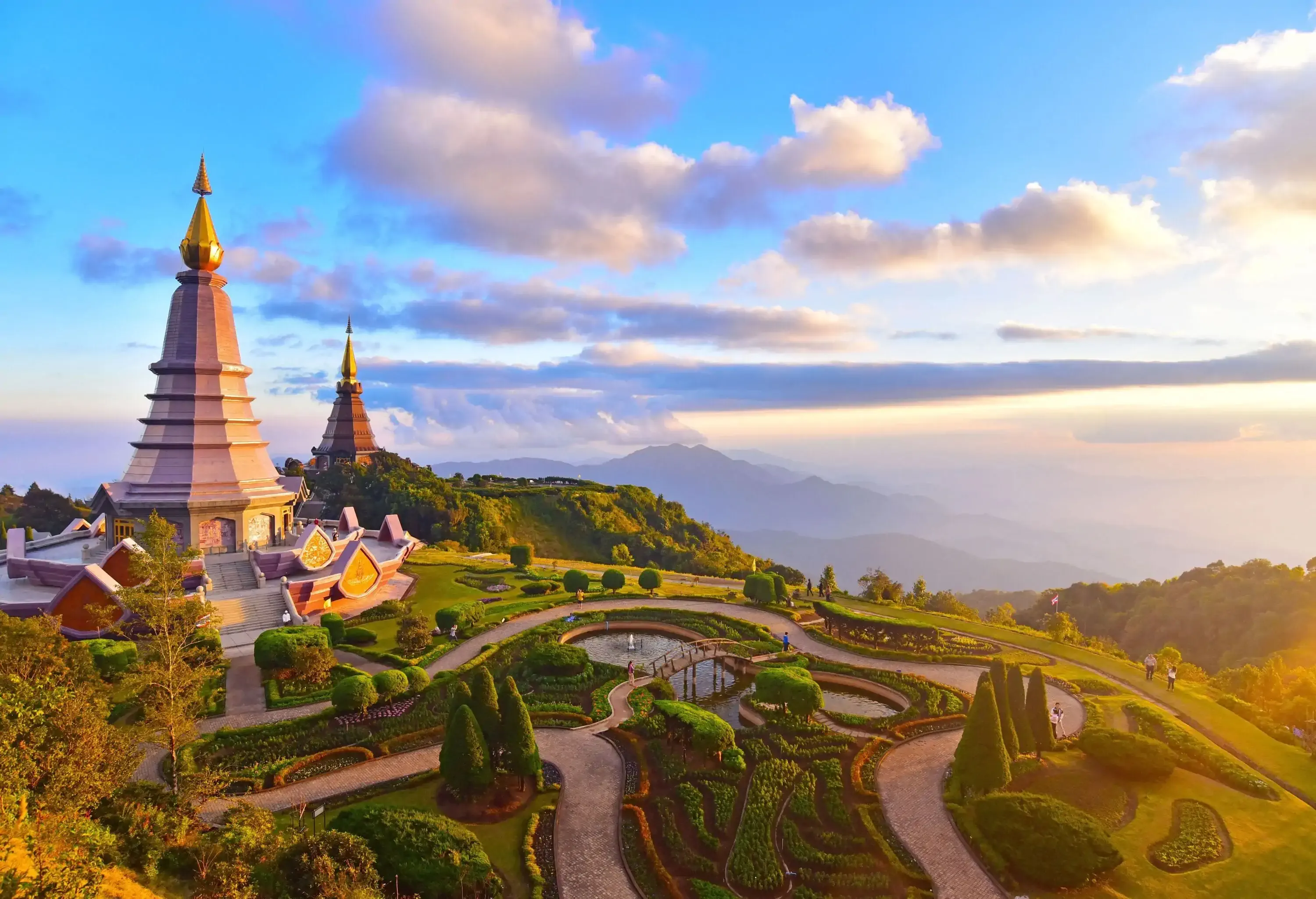 Two towering pagodas on top of a lush mountain with a beautiful garden landscape.