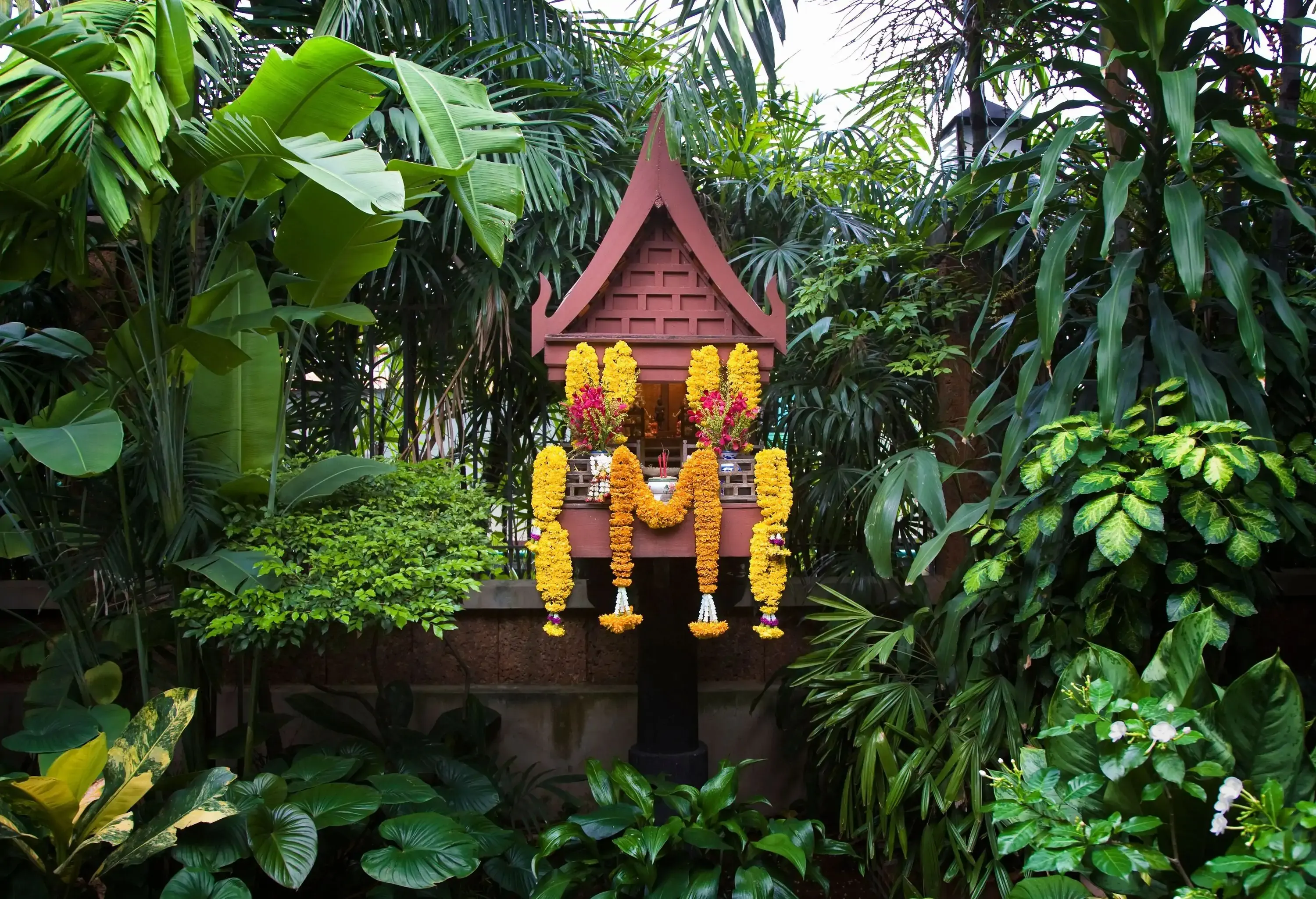 Yellow flower offerings hanged at the Spirit House in the gardens.