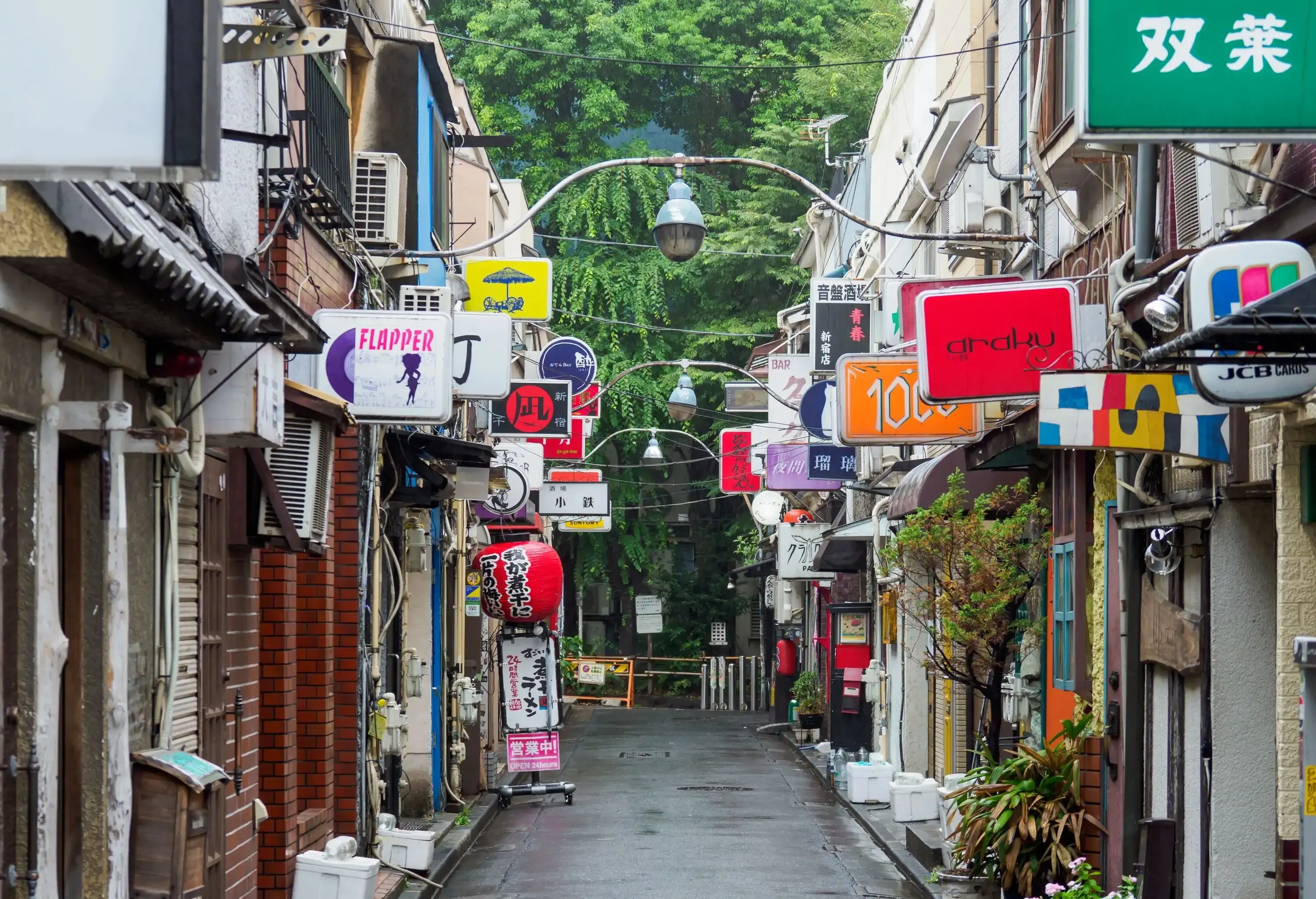 A wet alleyway surrounded by shops with colourful storefronts.
