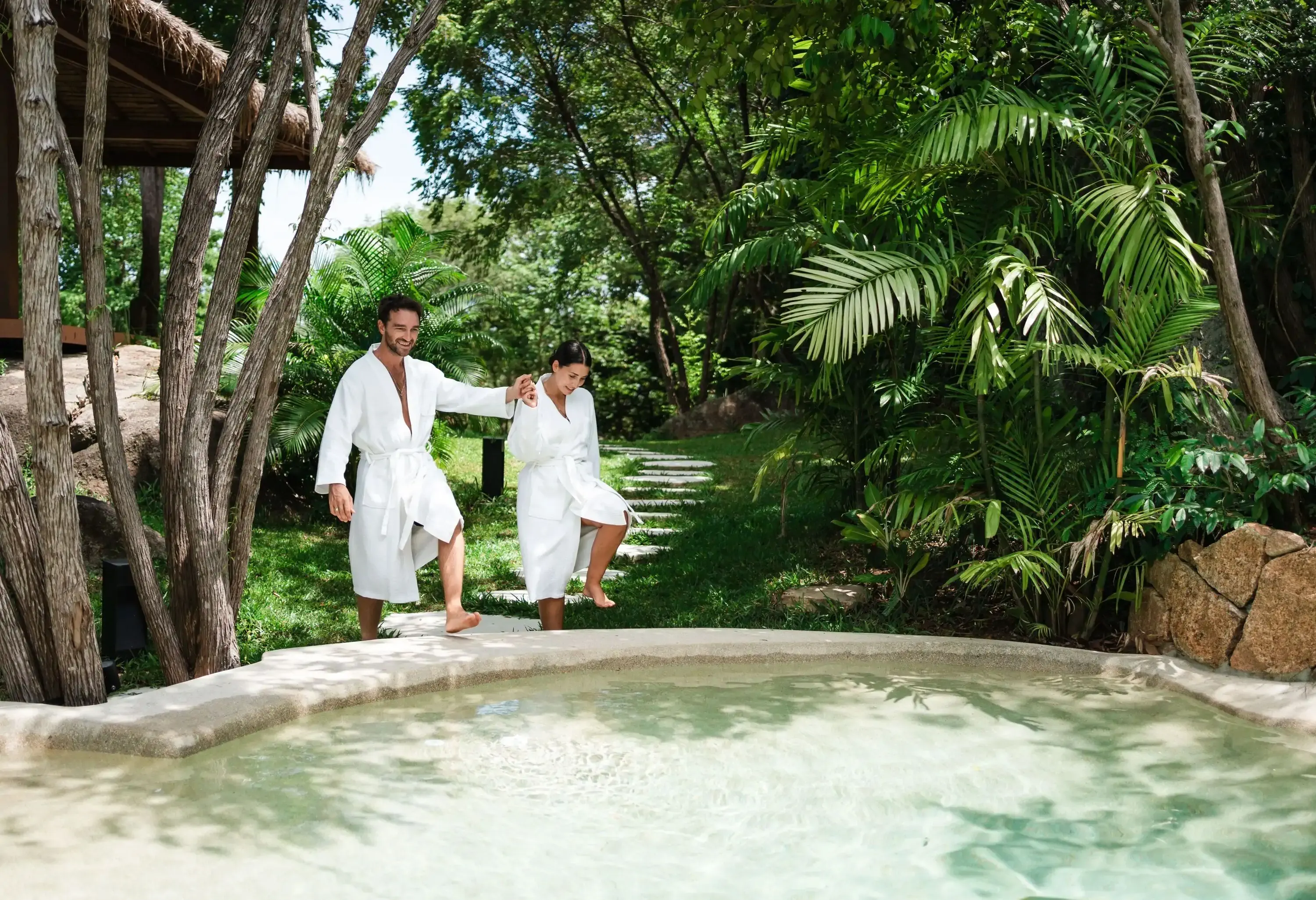 Smiling couple walking toward the cold pool after sauna on their vacation in a luxury villa.