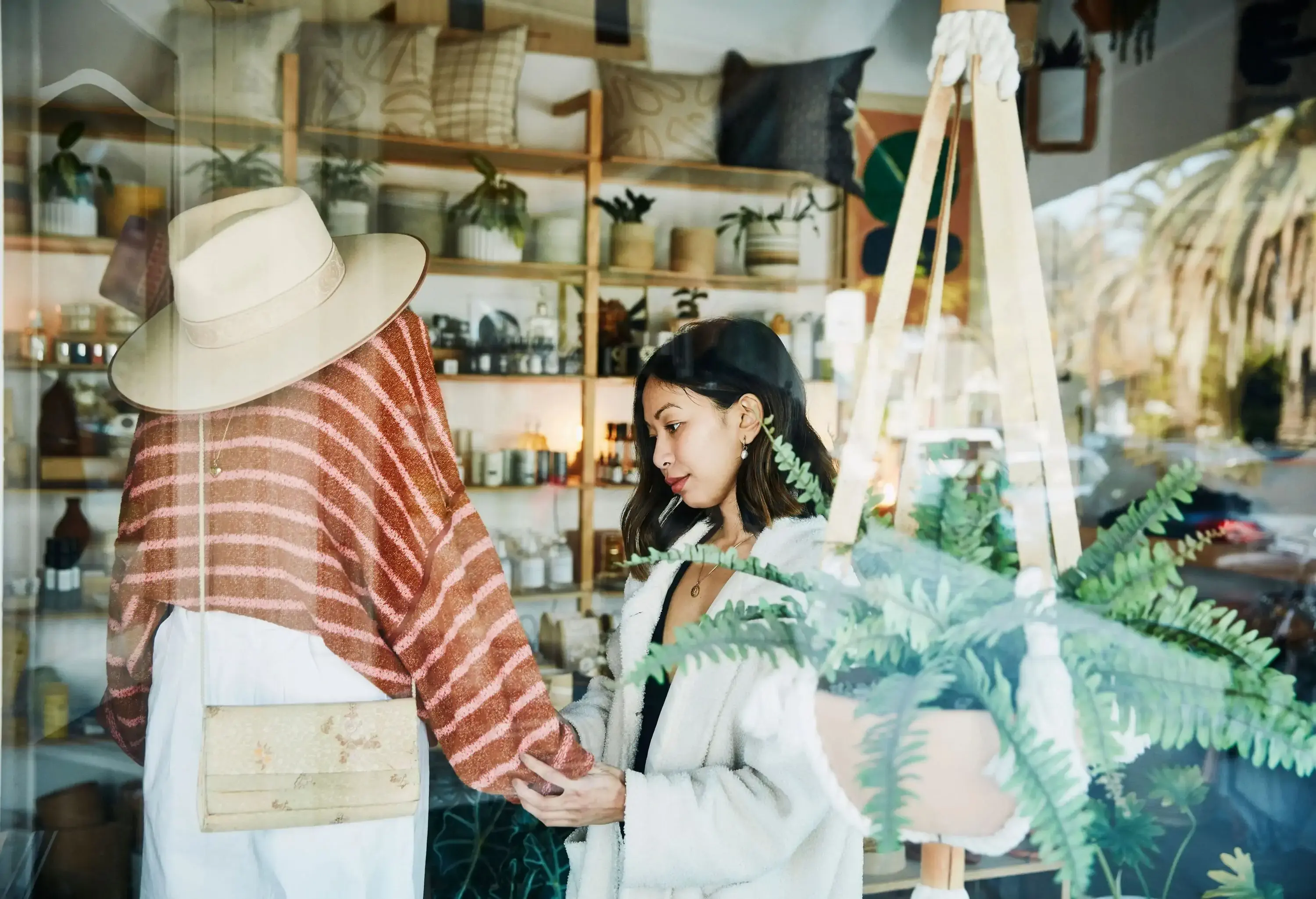 A woman examines the clothes in a mannequin inside a shop.