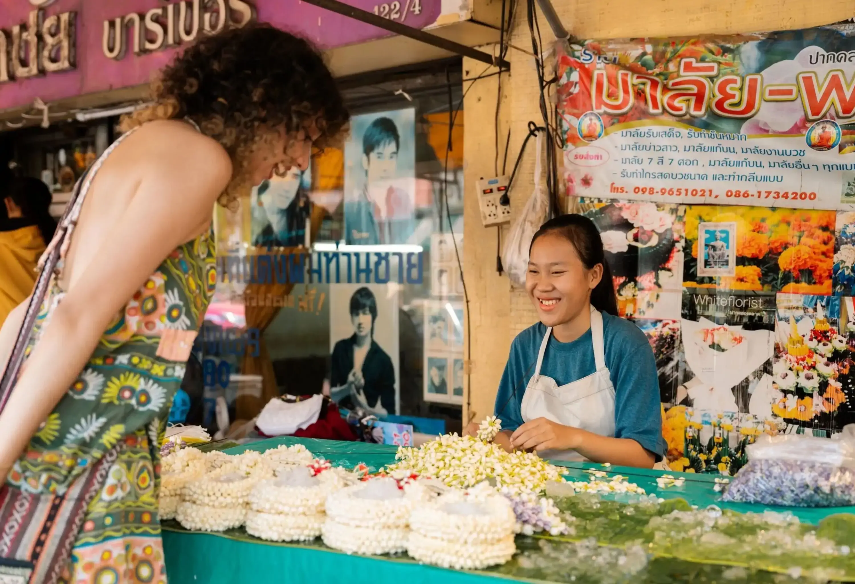 Asian hipster woman admiring flowers at the market stall while exploring Bangkok on holiday.