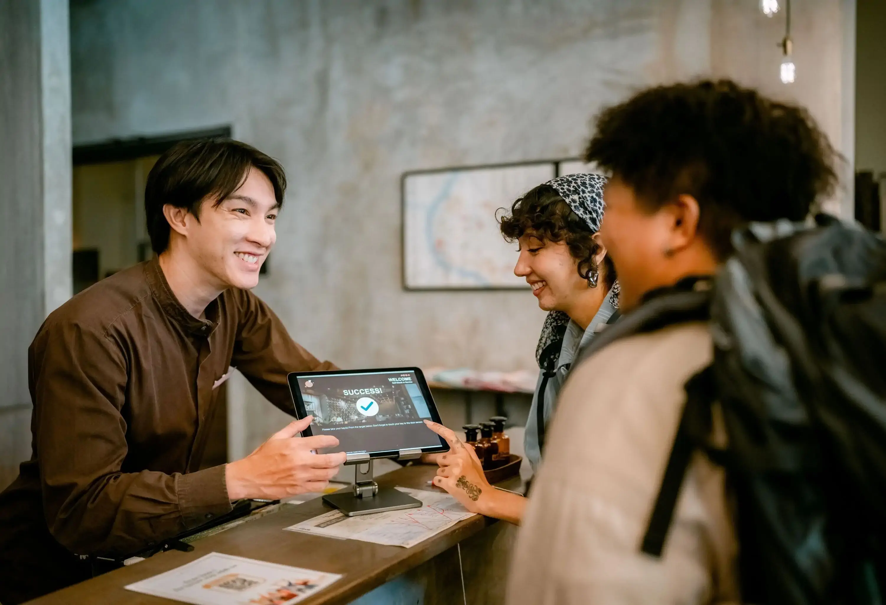 Asian backpackers arriving and registering with a digital tablet at reception.