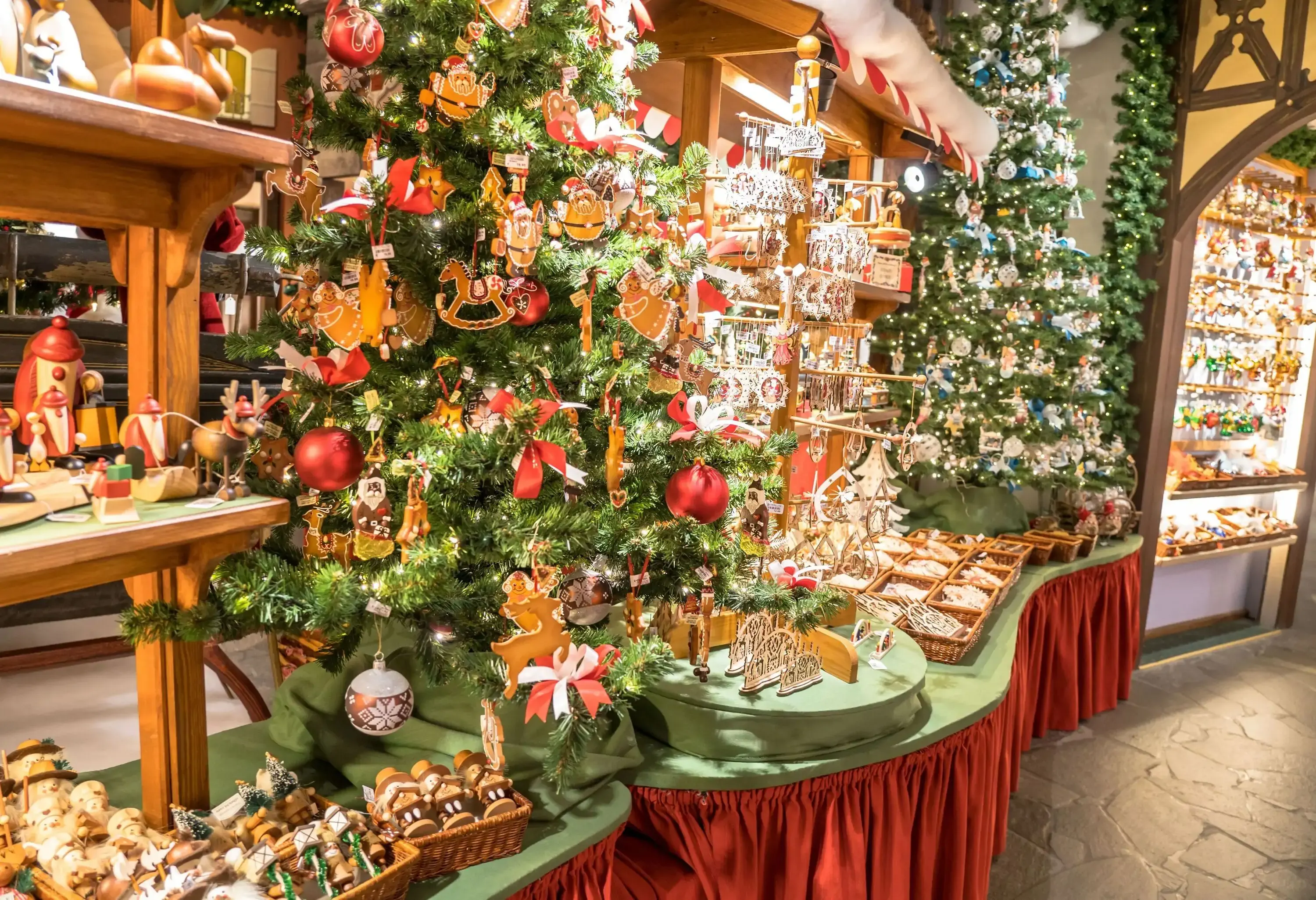 An array of Christmas ornaments in wooden baskets and decorated Christmas trees in a store.