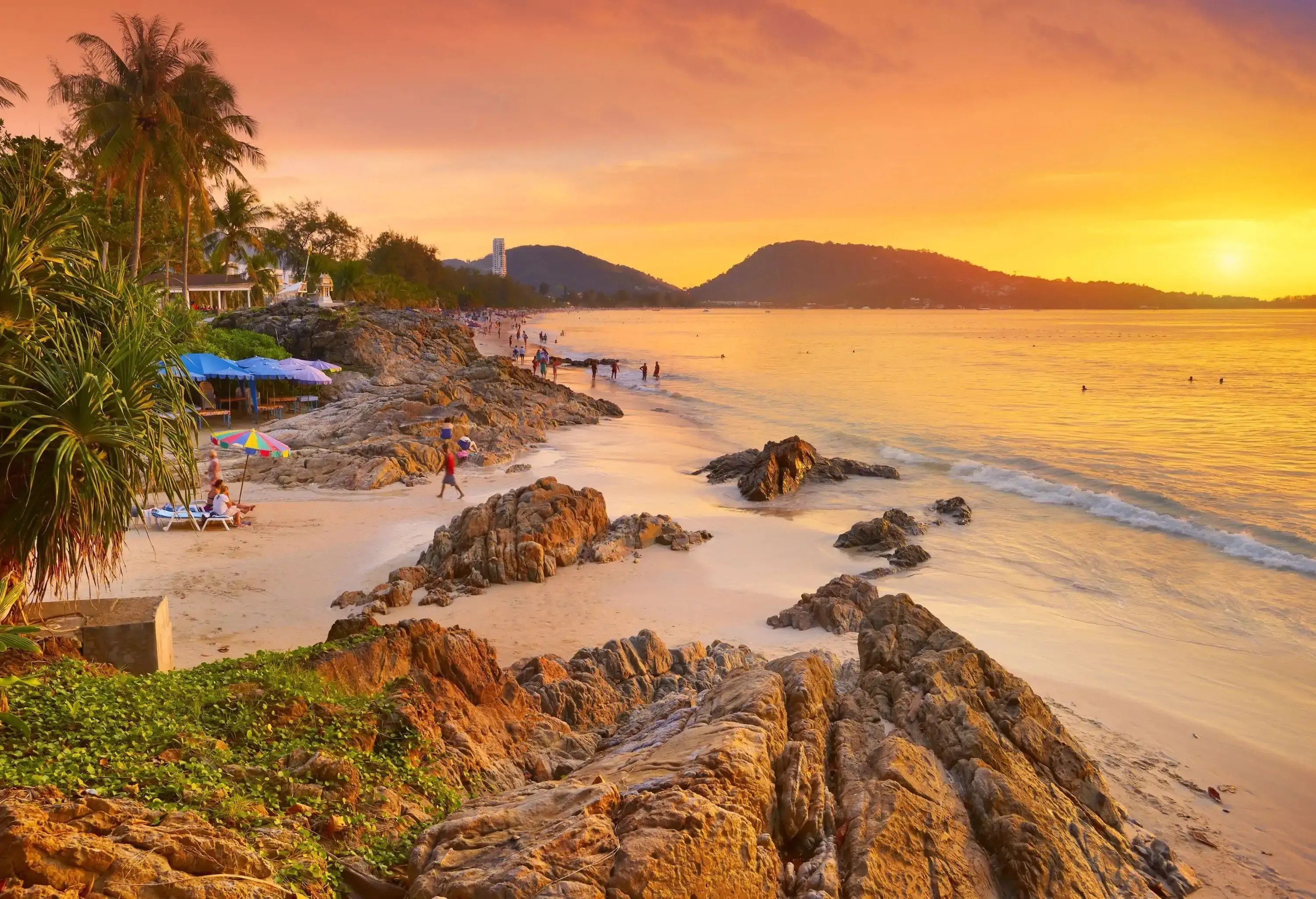 A beach with huge coastal rocks and views of a stunning sunset.