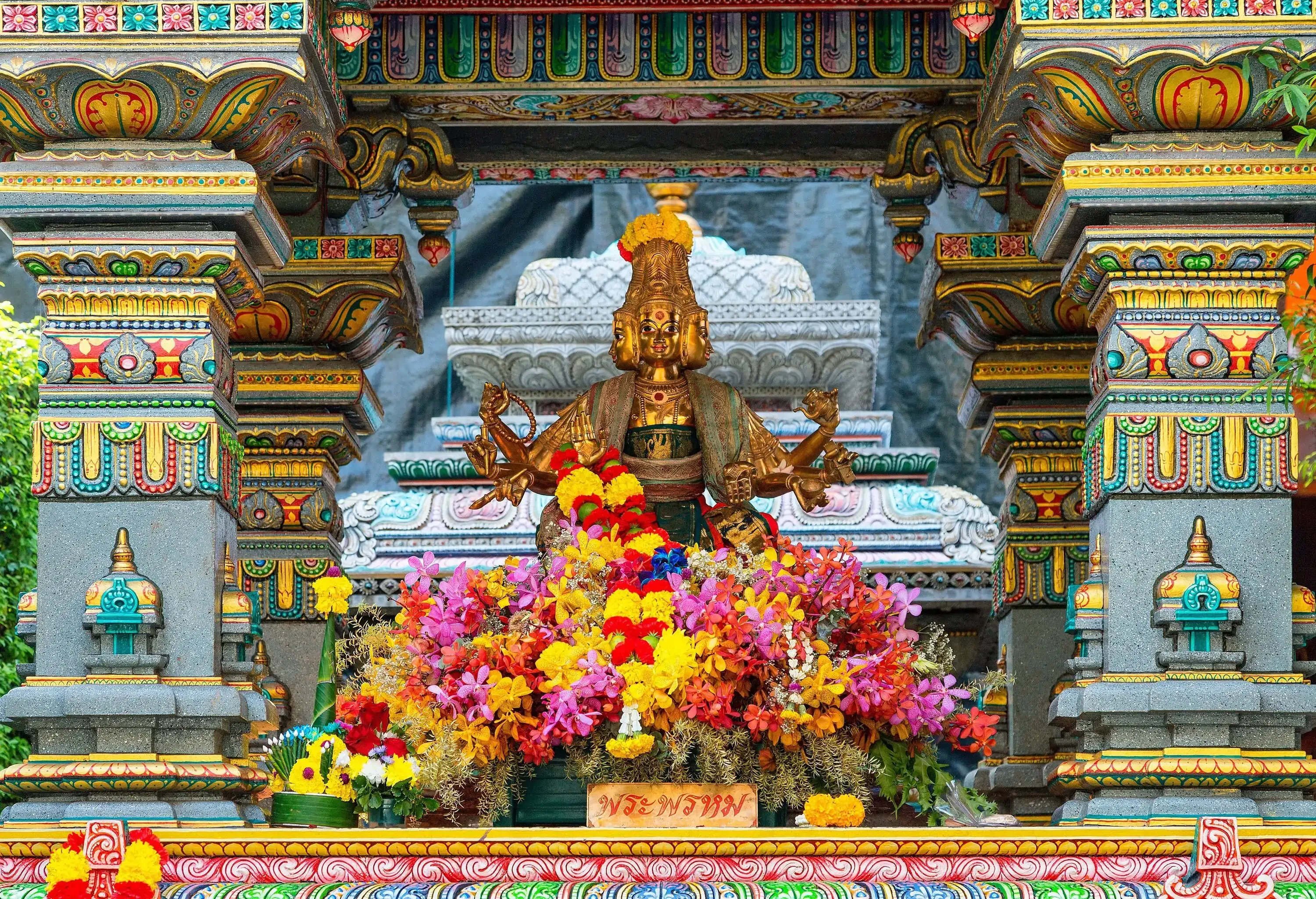 A colourful exterior detail of the temple's altar has a golden statue with three heads in the centre.