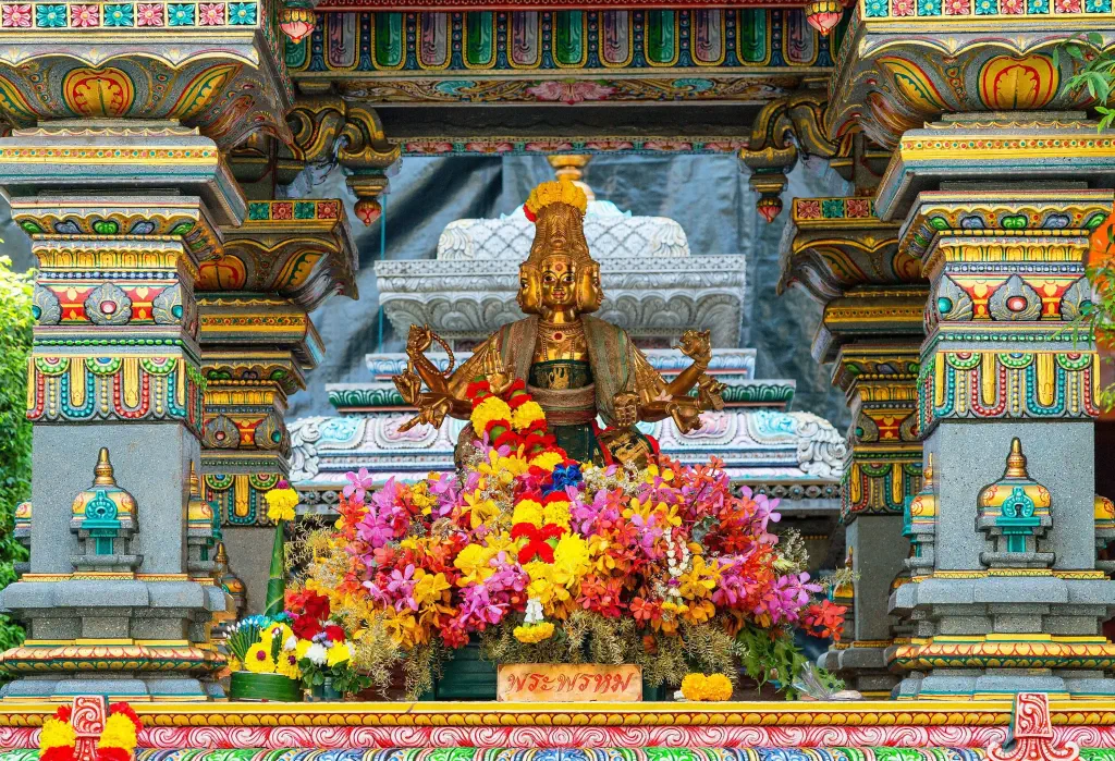 A colourful exterior detail of the temple's altar has a golden statue with three heads in the centre.