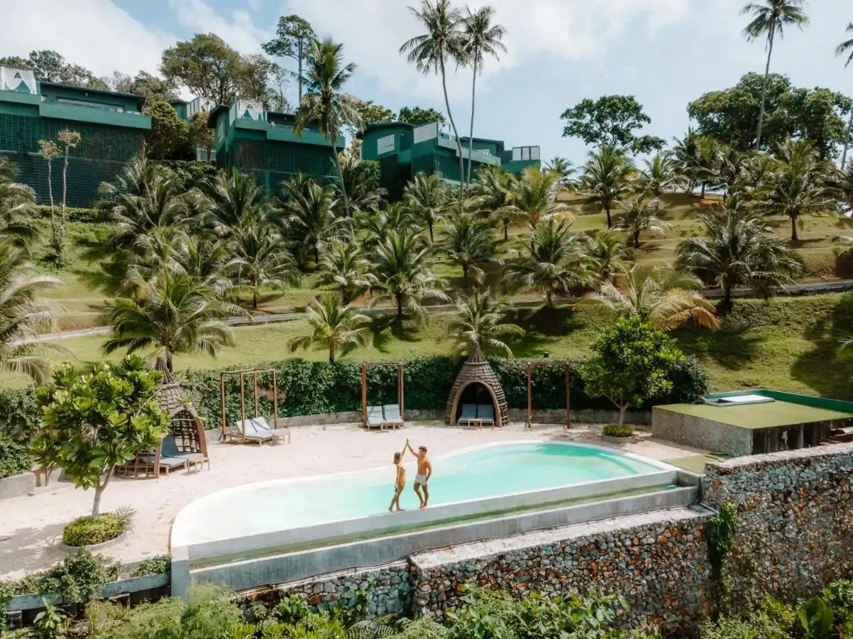 Drone view of a couple dancing by the infinity pool of a tropical hotel resort