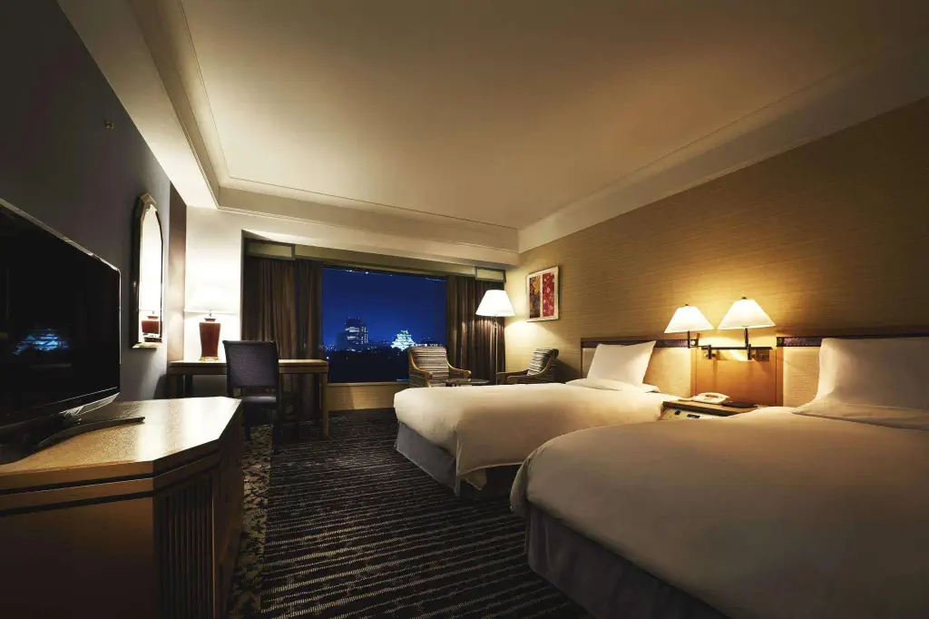 Hotel room with two double beds and view over illuminated city landmark at night