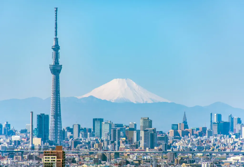 The iconic Tokyo Skytree dominates the city skyline, while a majestic cone-shaped mountain looms in the distance.