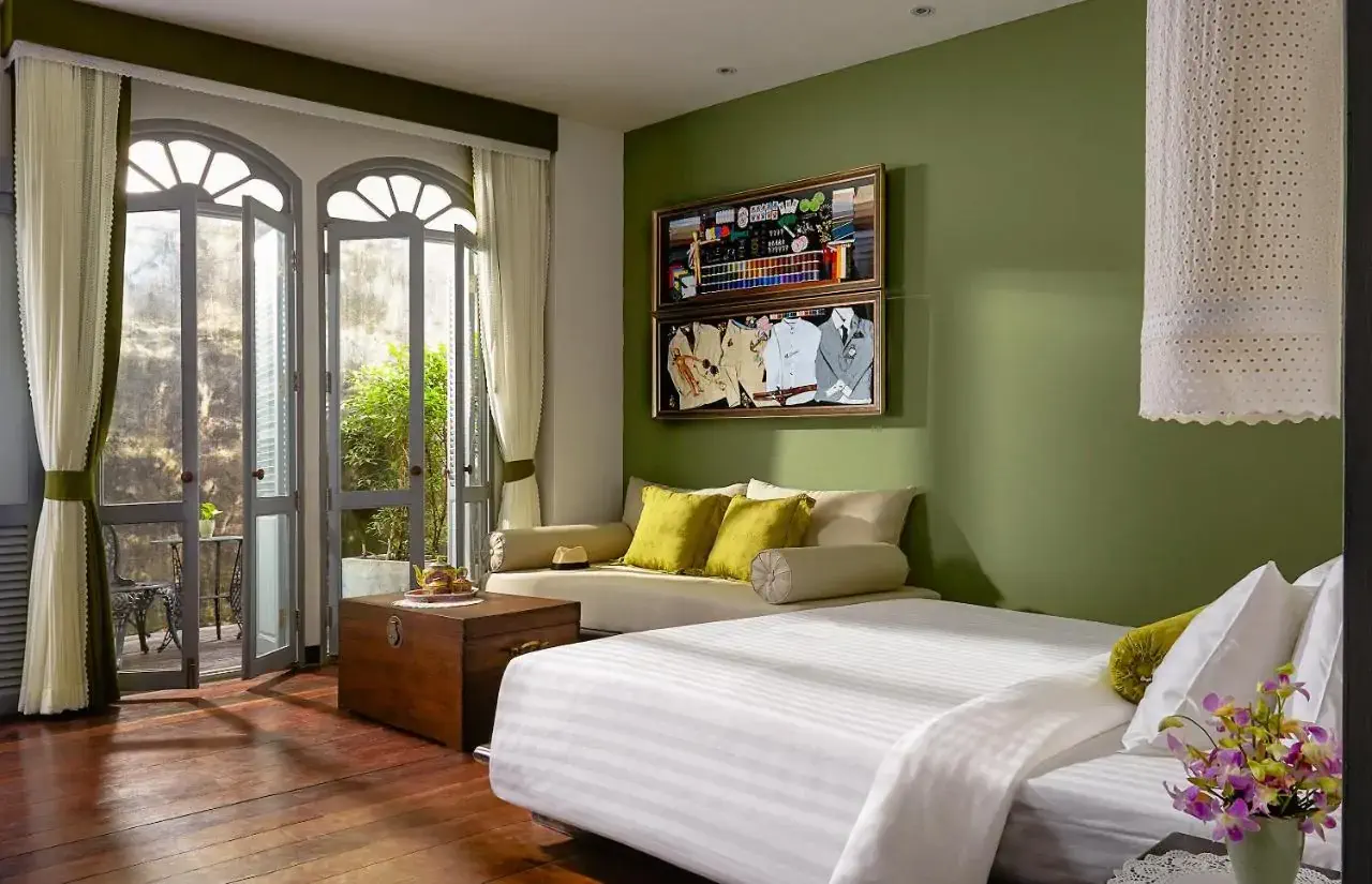 A green retro style hotel room with french doors overlooking greenery and artworks on the wall