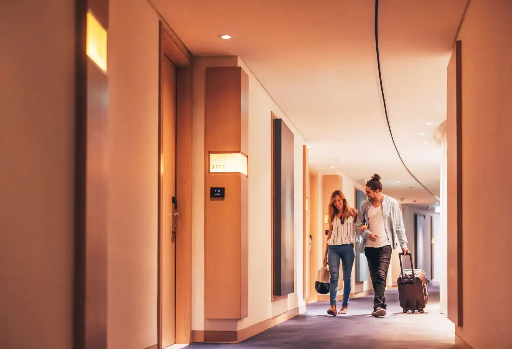 Couple walking with their luggage in the hotel corridor
