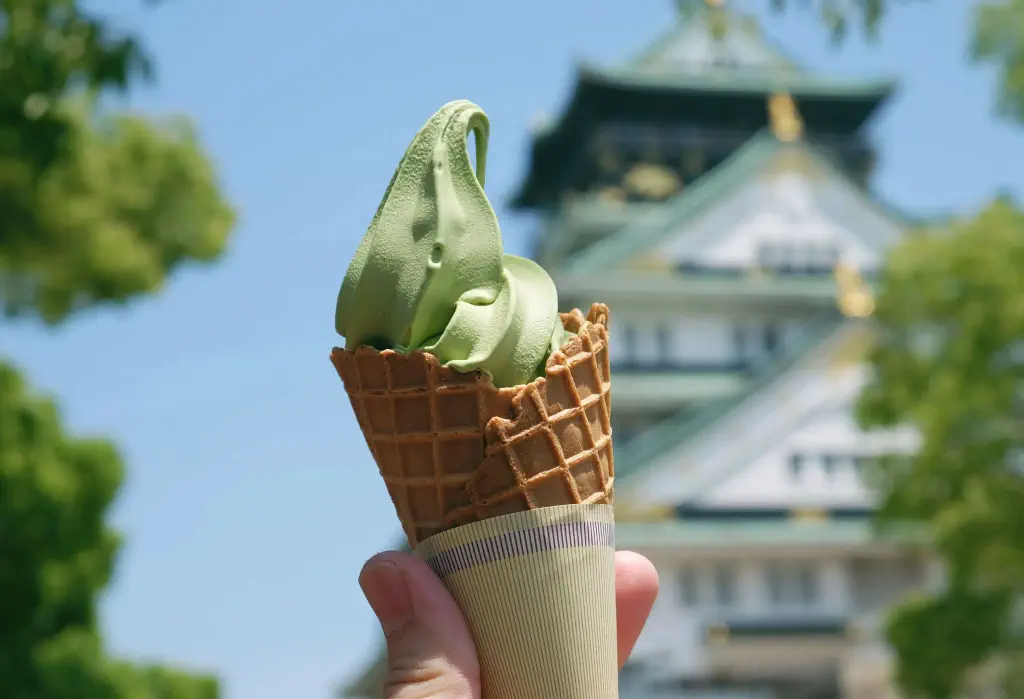 Matcha-flavoured ice cream in a sugar cone being raised in the air.
