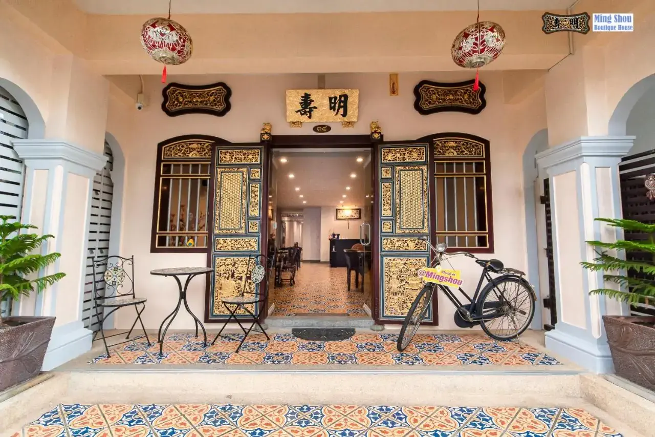A hotel entrance patio with antique tales, wooden carved door and a bike parked in the front