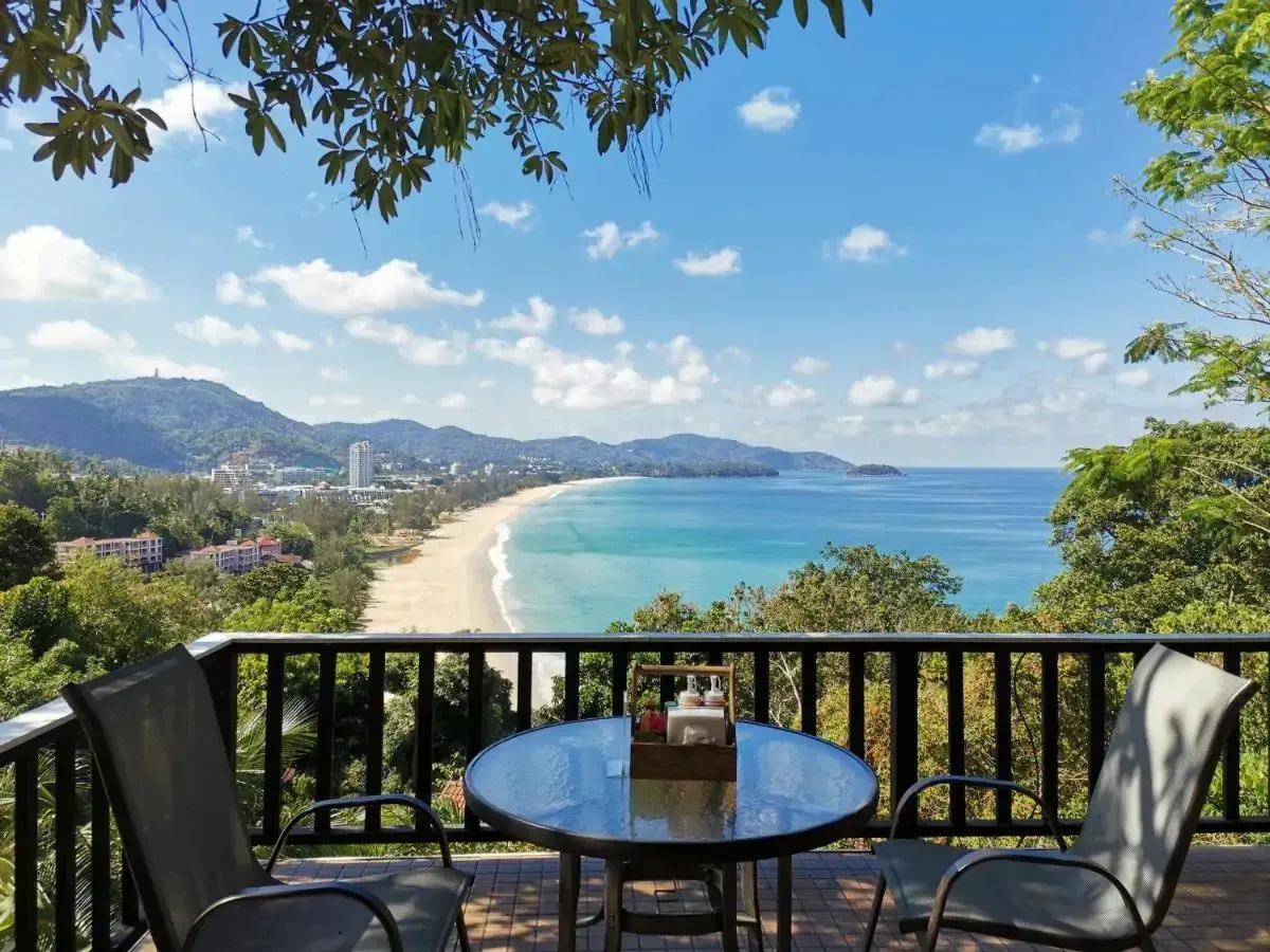 A terrace surrounded by greenery overlooking a white sandy beach