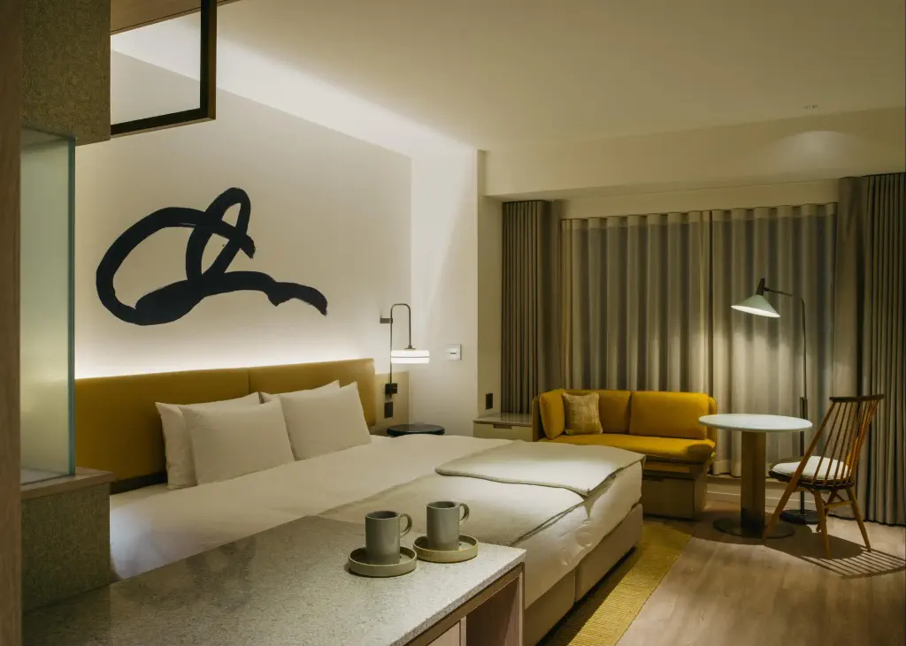 A contemporary minimalist hotel room in neutral tones and feature signature on a wall