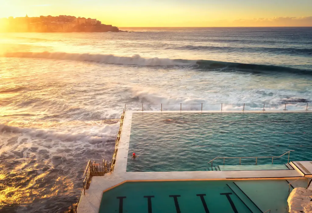The iconic Bondi Beach, with its rolling waves, is beautifully complemented by a crystal-clear swimming pool nestled along the shore.