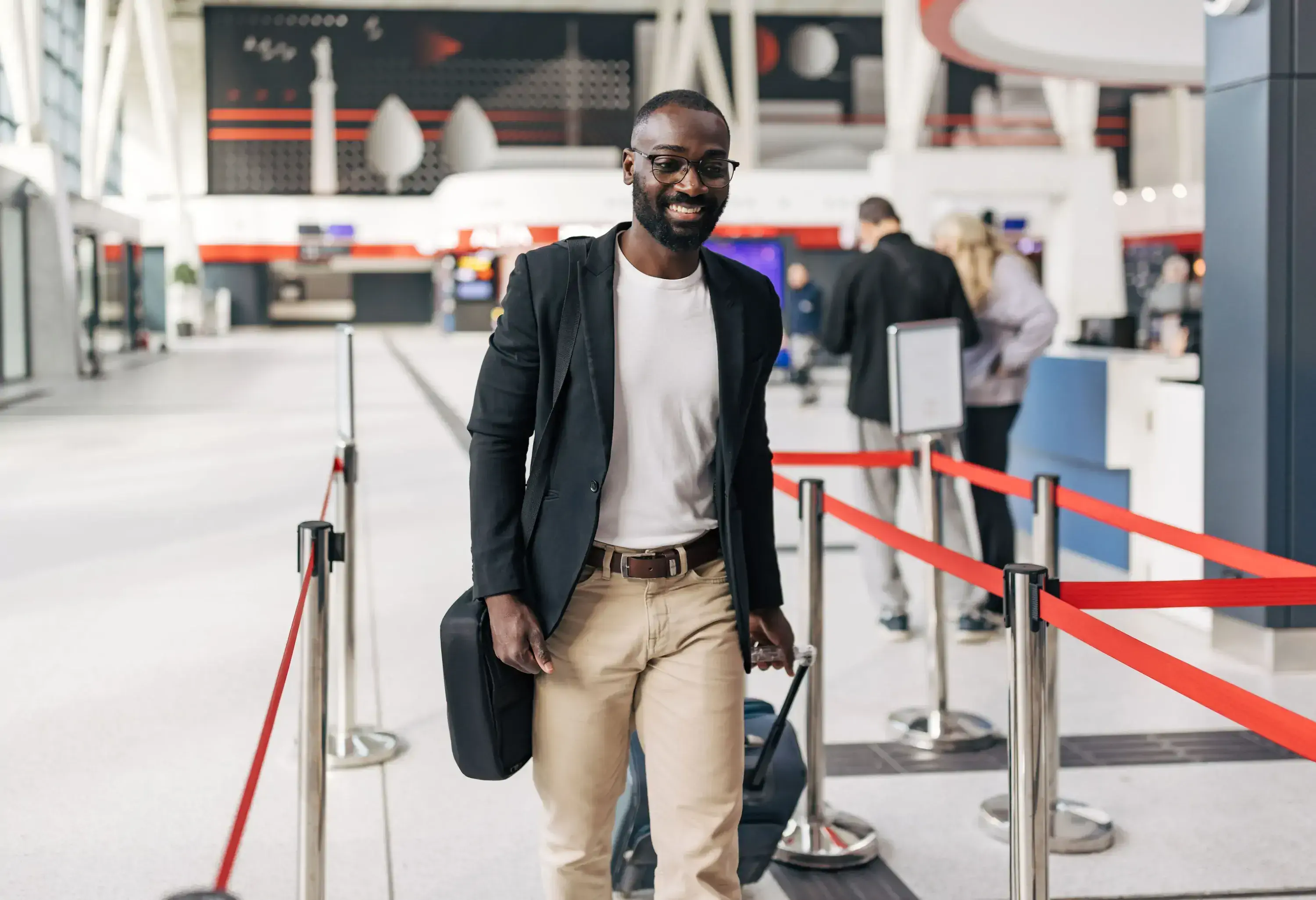 Businessman walking through the bustling airport terminal, pulling a suitcase and carrying a briefcase, exuding confidence while preparing to board the upcoming flight