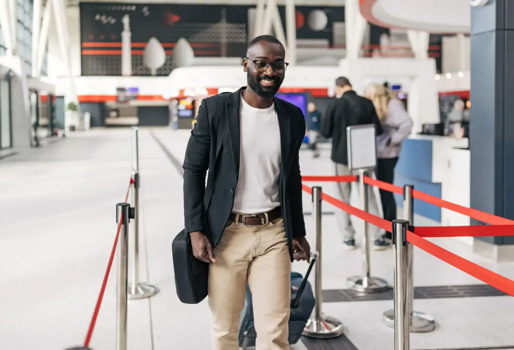 Businessman walking through the bustling airport terminal, pulling a suitcase and carrying a briefcase, exuding confidence while preparing to board the upcoming flight