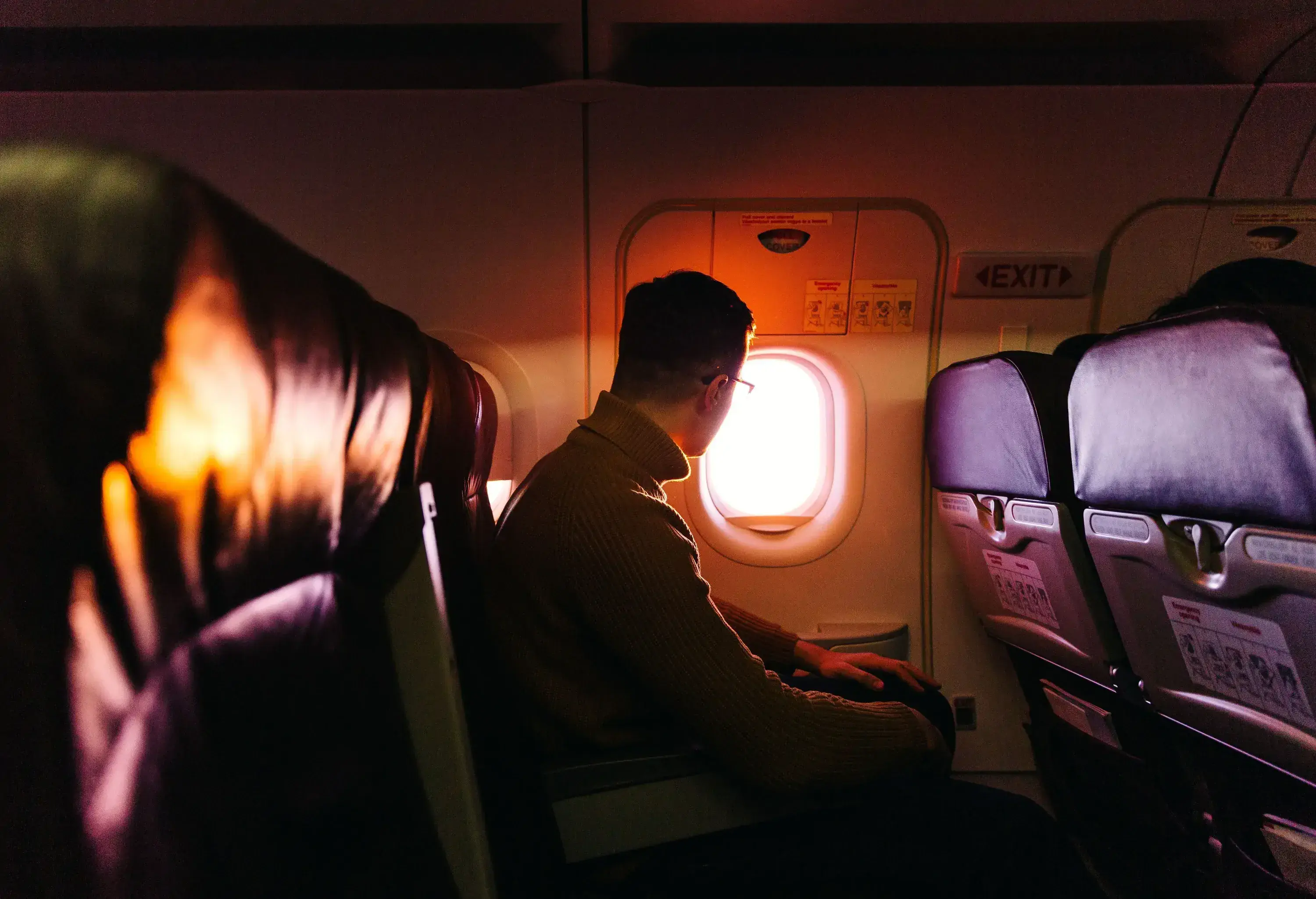 a man looking out the airplane window during sunset