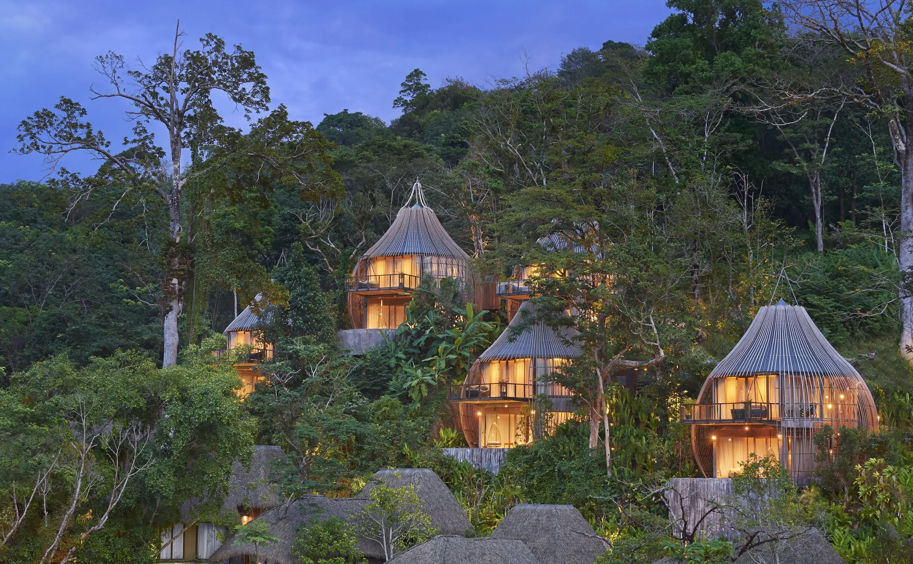 Tree houses in a tropical resort on a hill at dusk